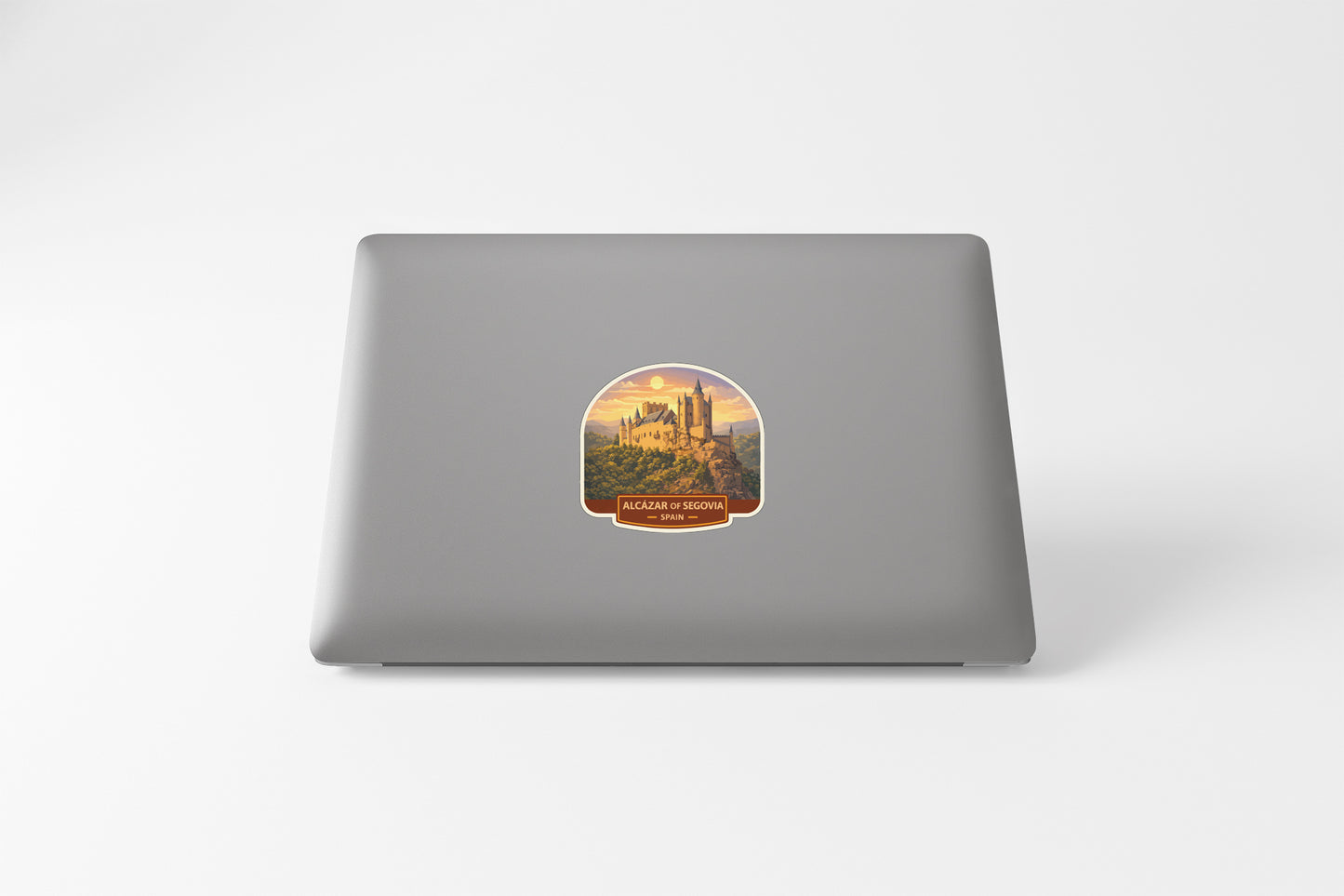 a sticker on the back of a laptop with a castle and a sunset in the background.
