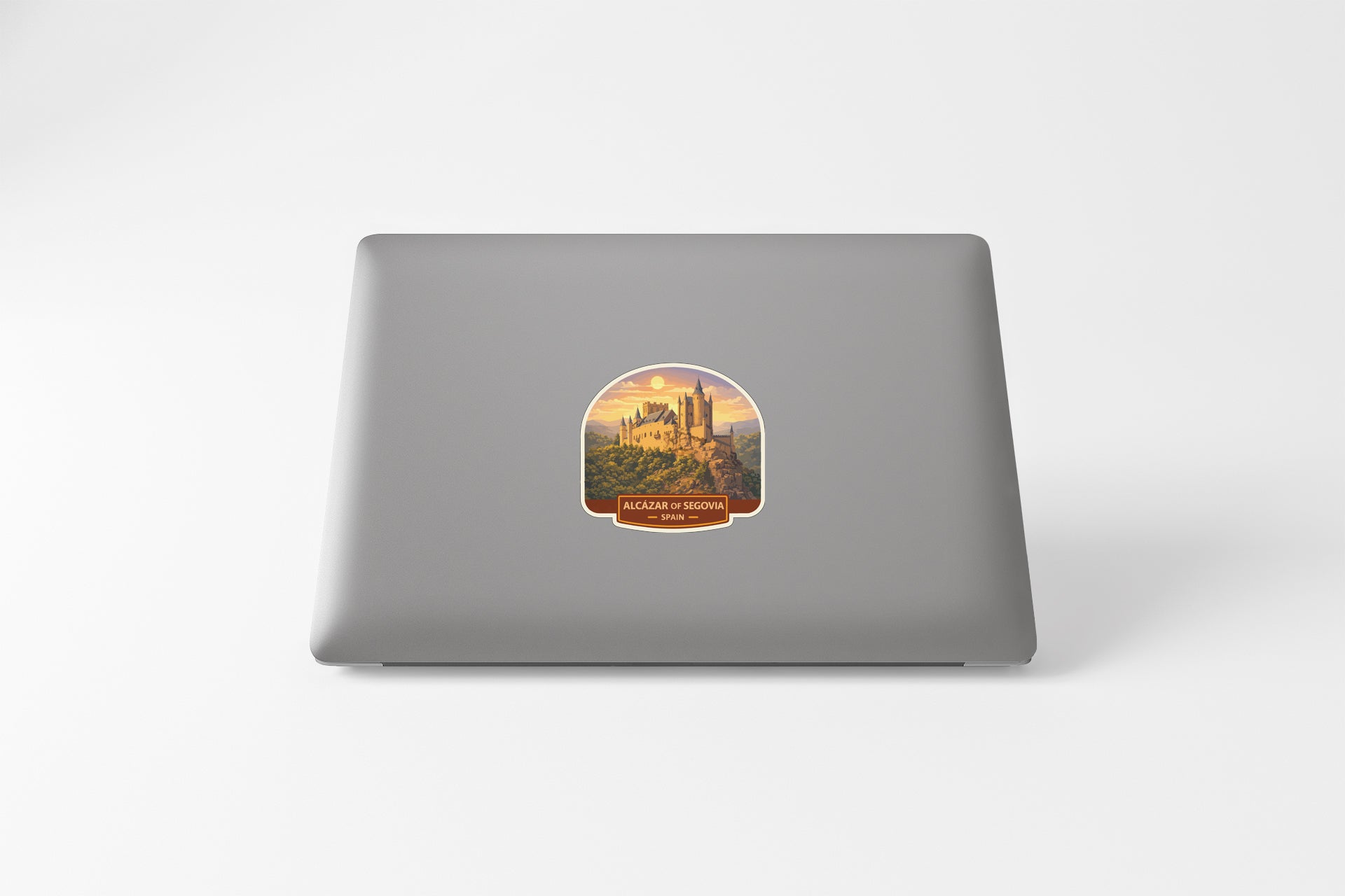 a sticker on the back of a laptop with a castle and a sunset in the background.