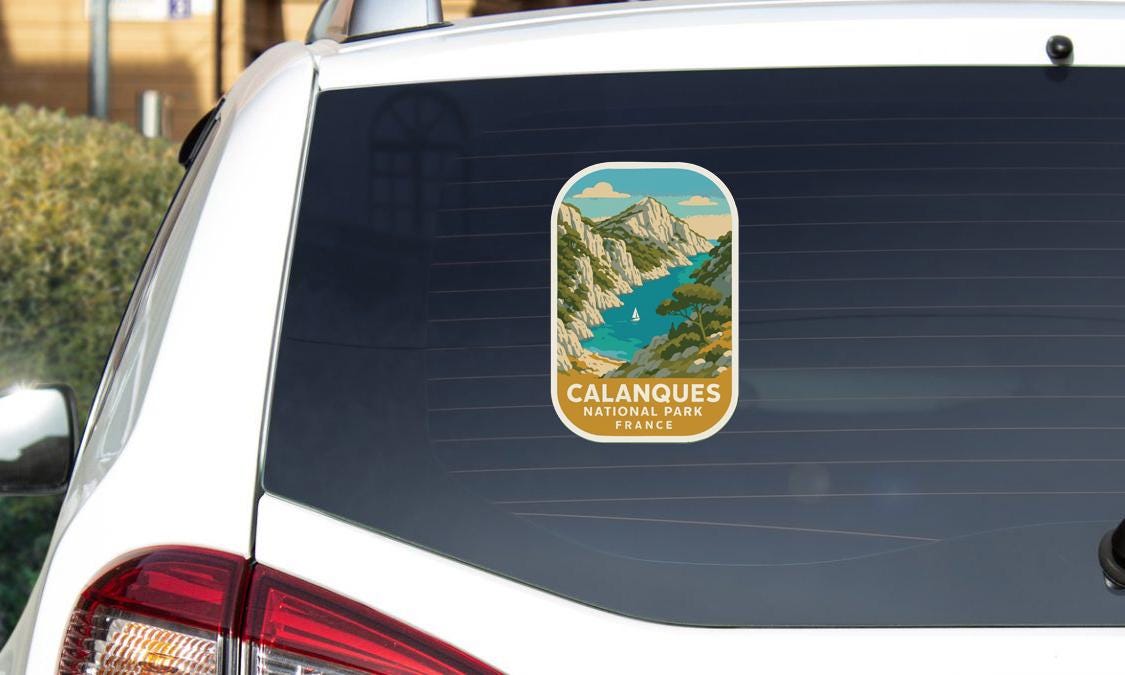 A sticker on the rear window of a white car, depicting a scenic landscape with mountains and a river.