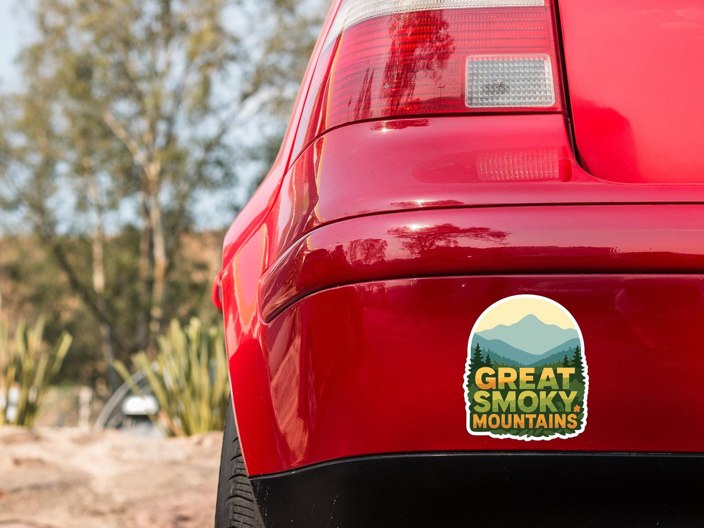 the rear end of a red car with a sticker on the trunk that says "Great Smoky Mountains".