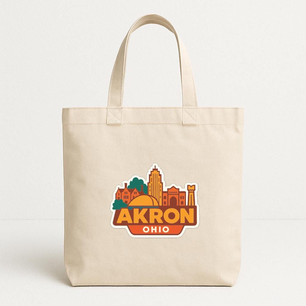 A beige tote bag with a graphic design featuring the city of Akron, Ohio.
