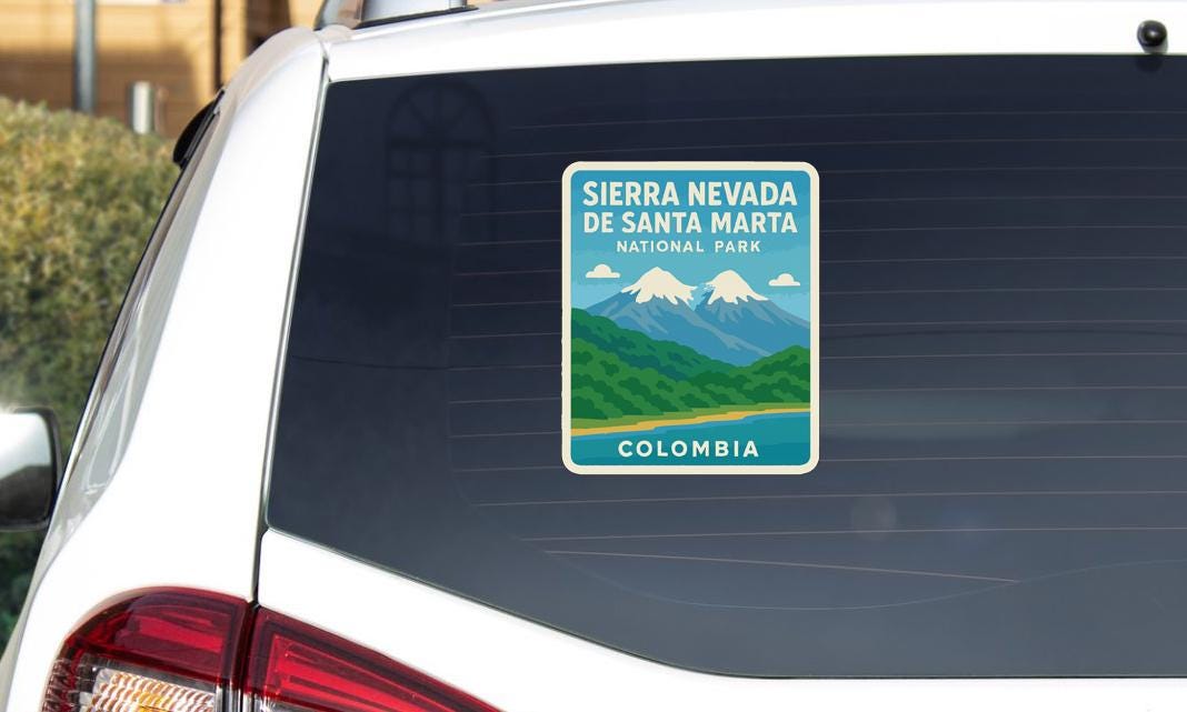 A sticker on the rear window of a car, depicting a scenic landscape with mountains and a river, indicating Sierra Nevada, Nevada, and Colombia.