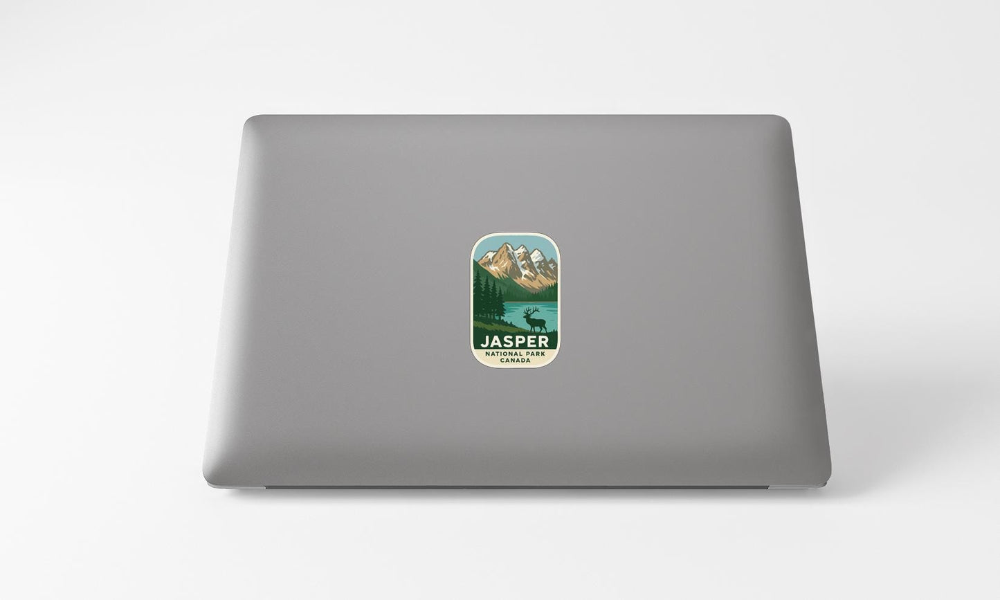 A sticker with a mountain landscape and a deer is placed on the back of a laptop computer.