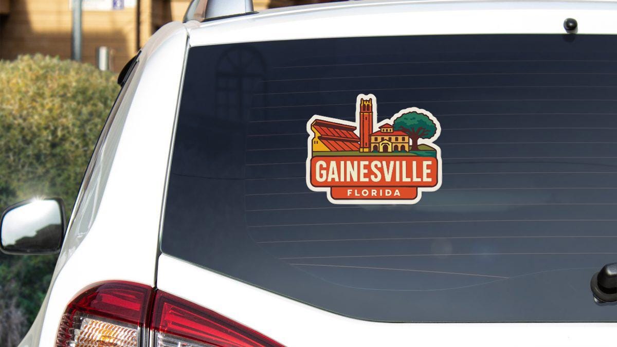 A sticker on the rear window of a white car that says "GAINESVILLE, FLORIDA".