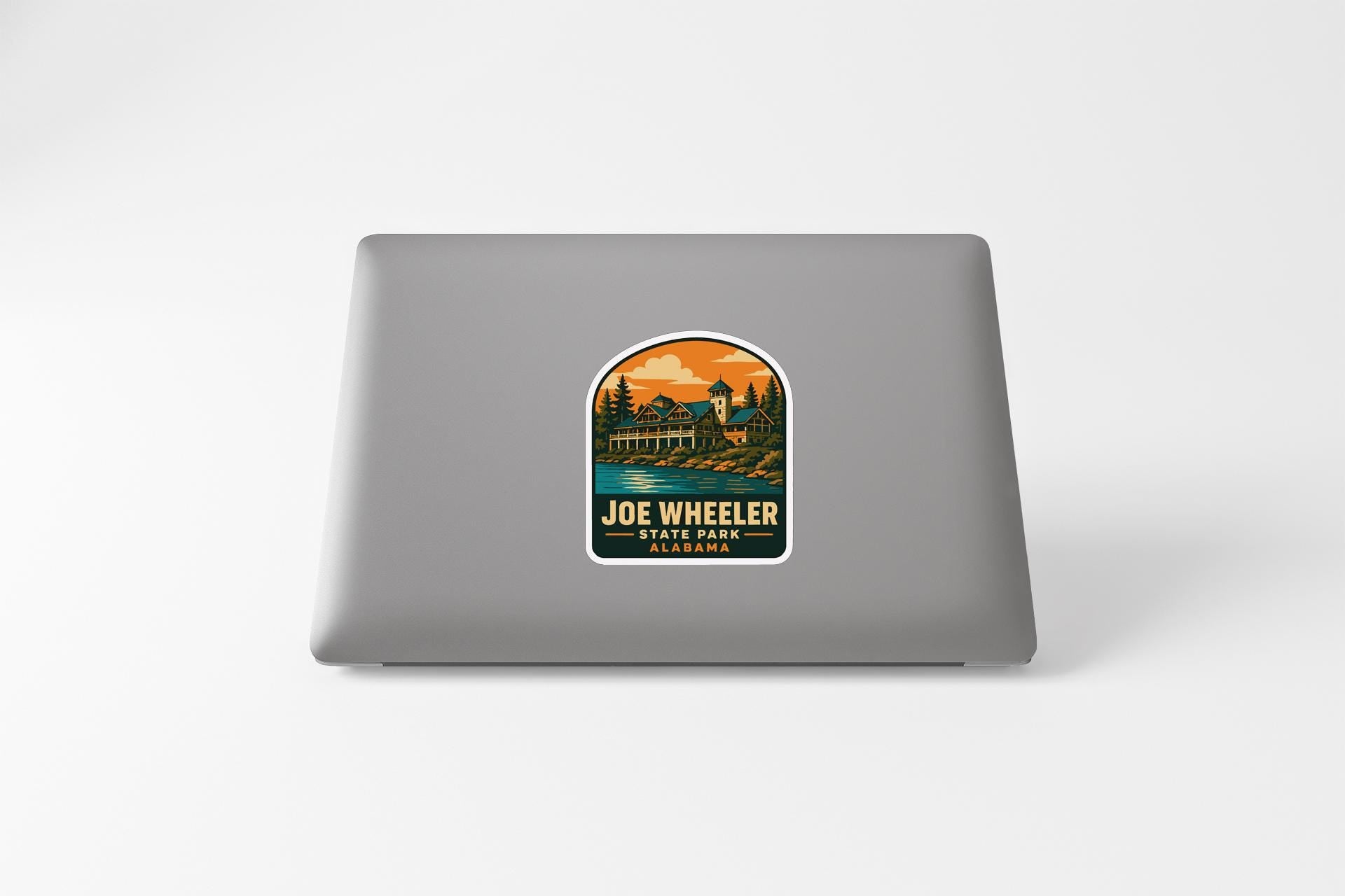 A sticker on the back of a laptop, depicting a scenic landscape with a bridge and trees.