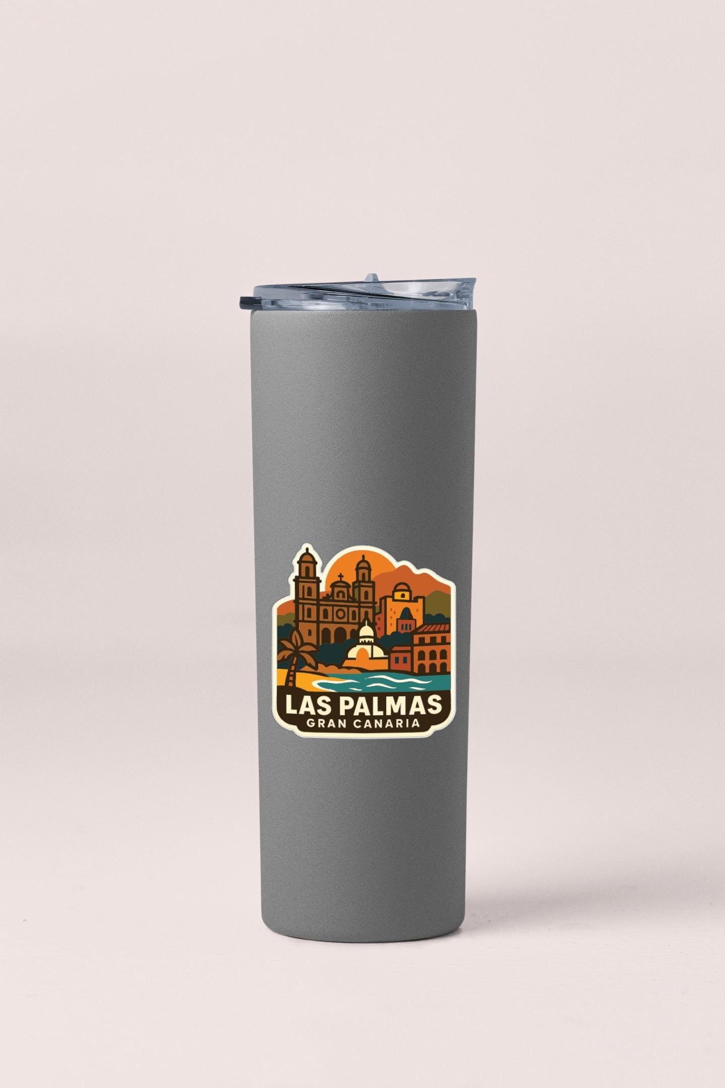 A gray insulated tumbler with a sticker depicting the city of Las Palmas, Gran Canaria.