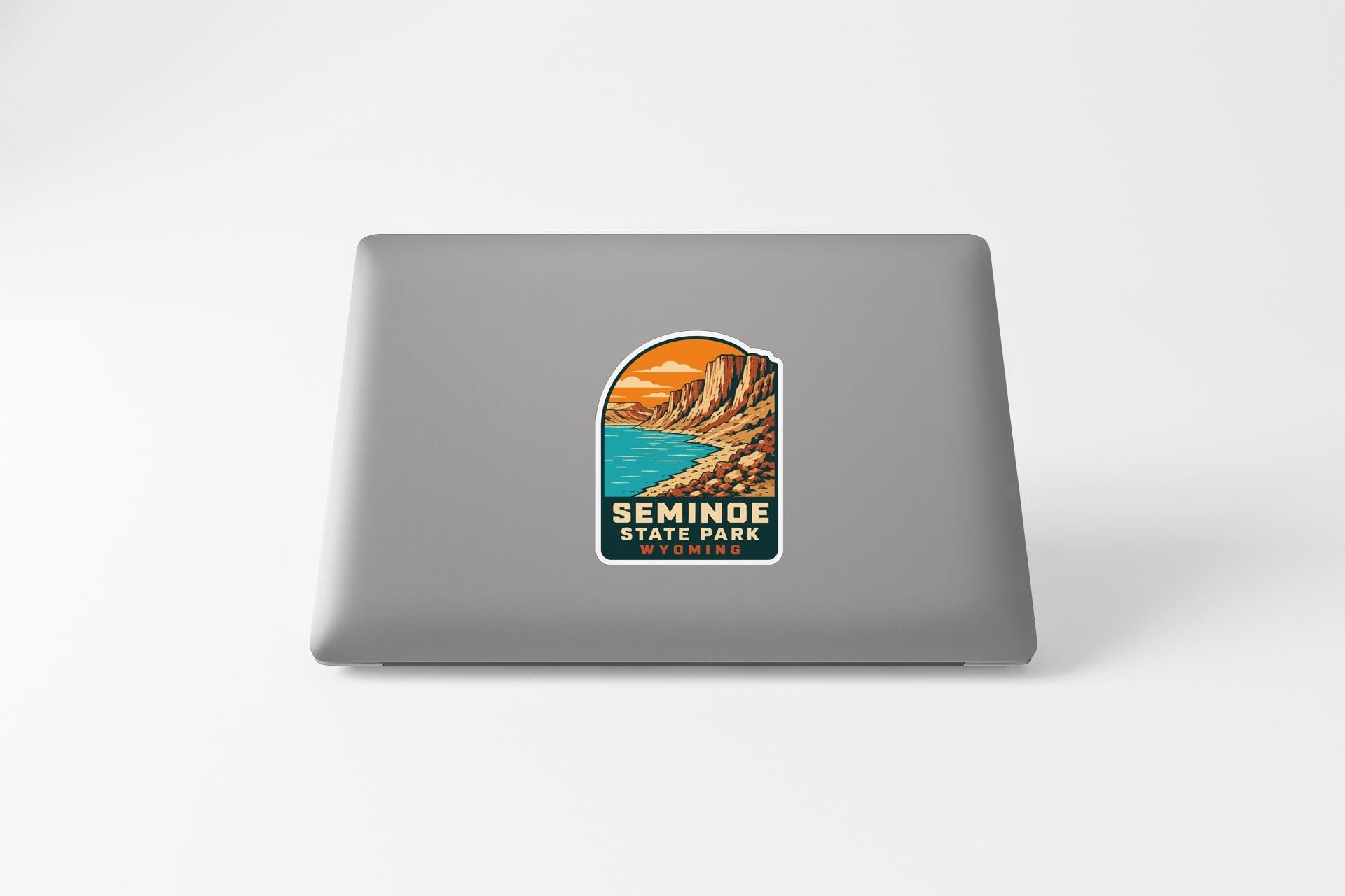 A sticker depicting a scenic landscape with mountains, water, and a sunset.