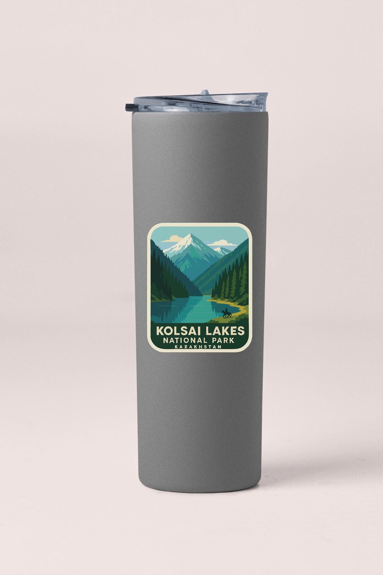 A gray insulated tumbler with a sticker depicting a scenic mountain landscape and a lake.