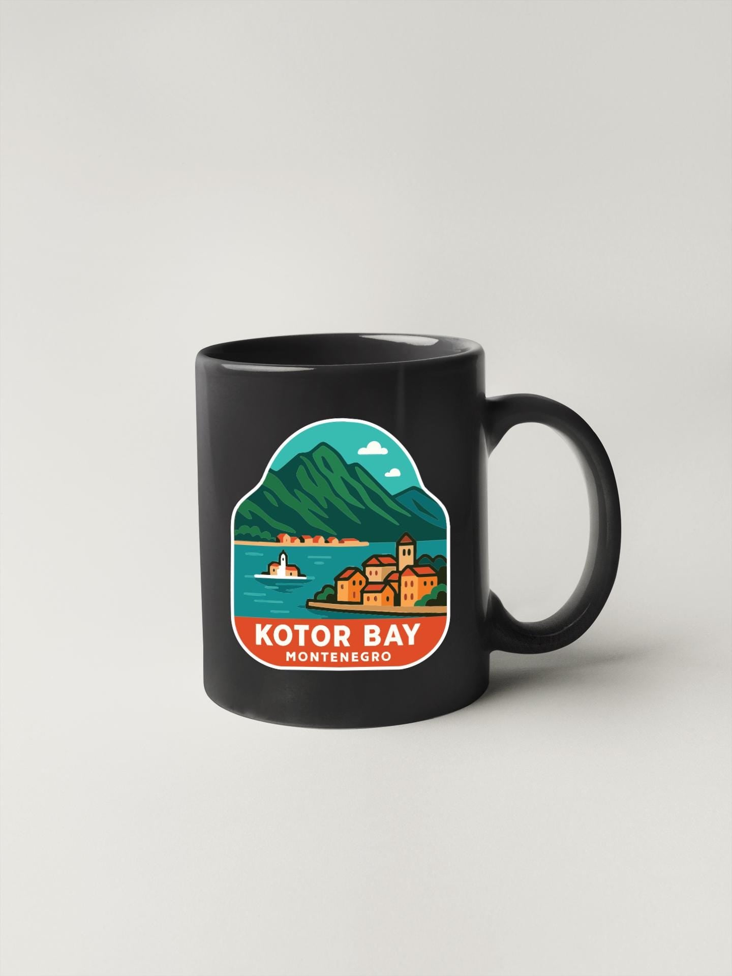 A black coffee mug with a graphic design depicting a scenic view of Kotor Bay, a coastal town in Montenegro.