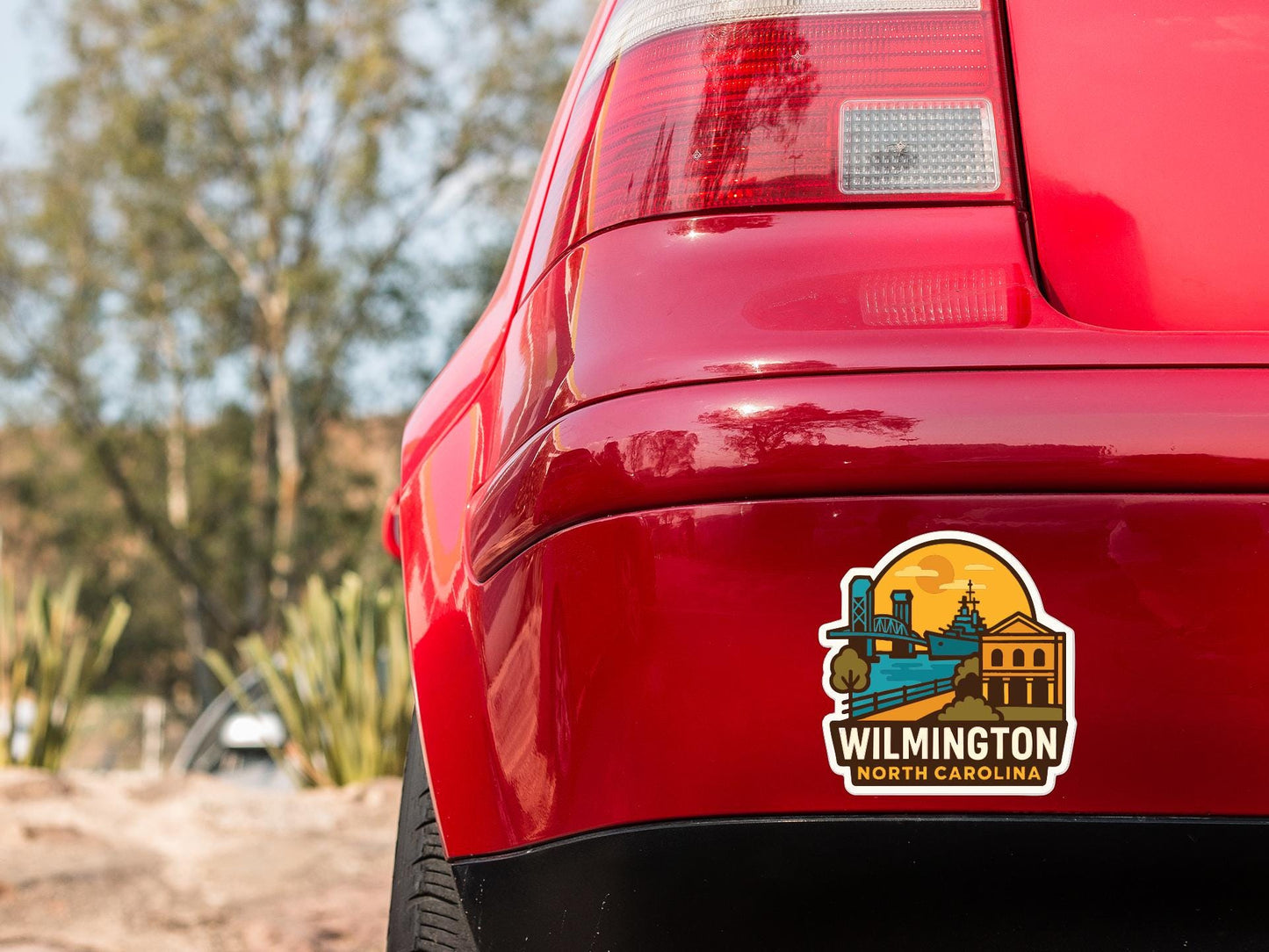 the rear end of a red car with a sticker on the trunk that says "Wilmington North Carolina".