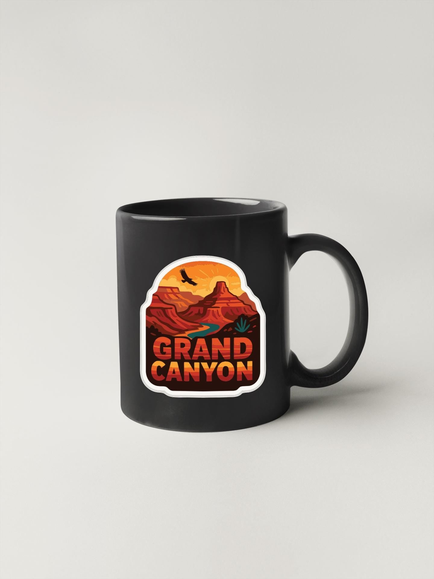 A black coffee mug with a graphic design depicting the Grand Canyon.