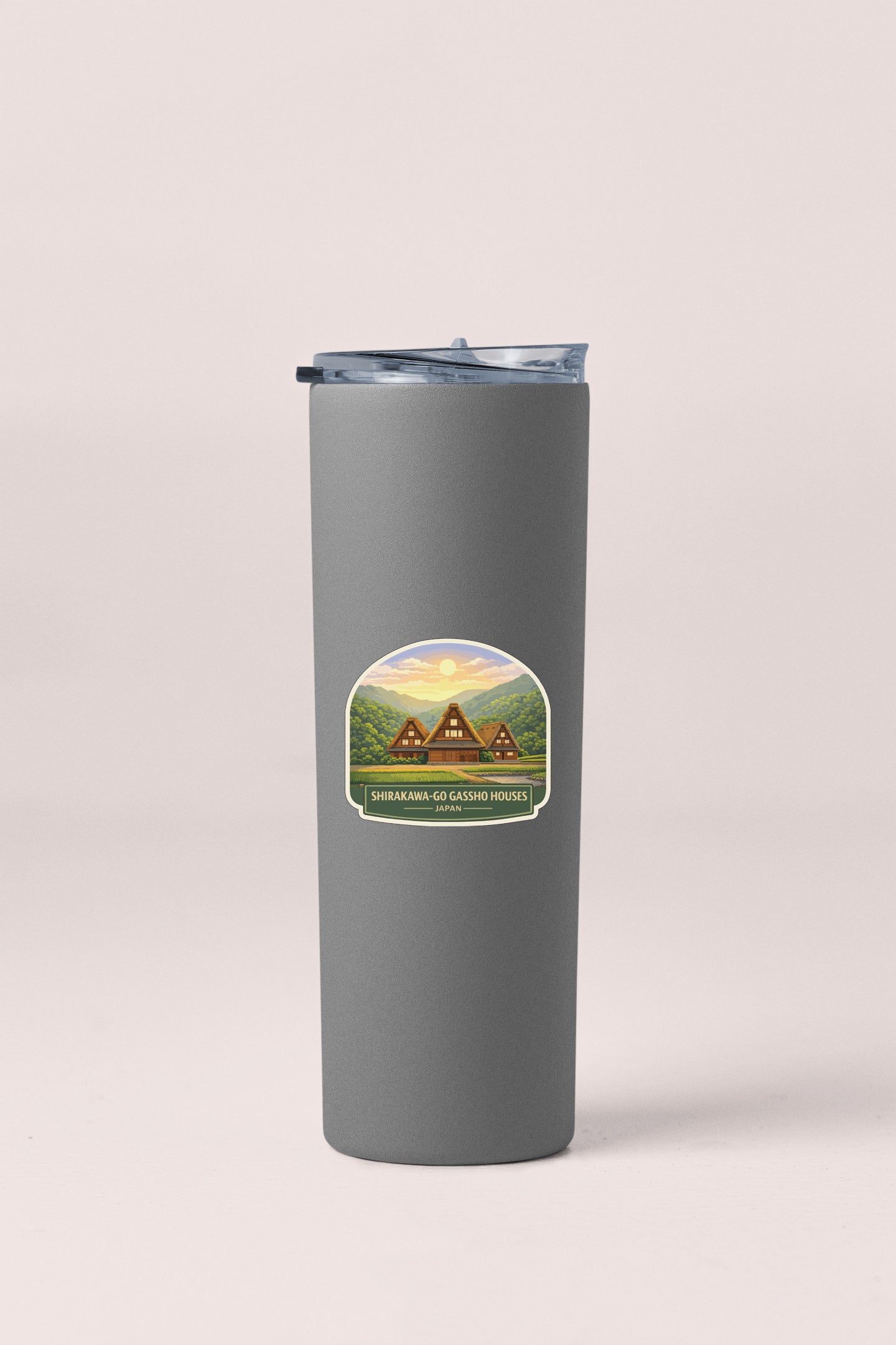 A gray insulated tumbler with a sticker depicting a scenic mountain landscape.