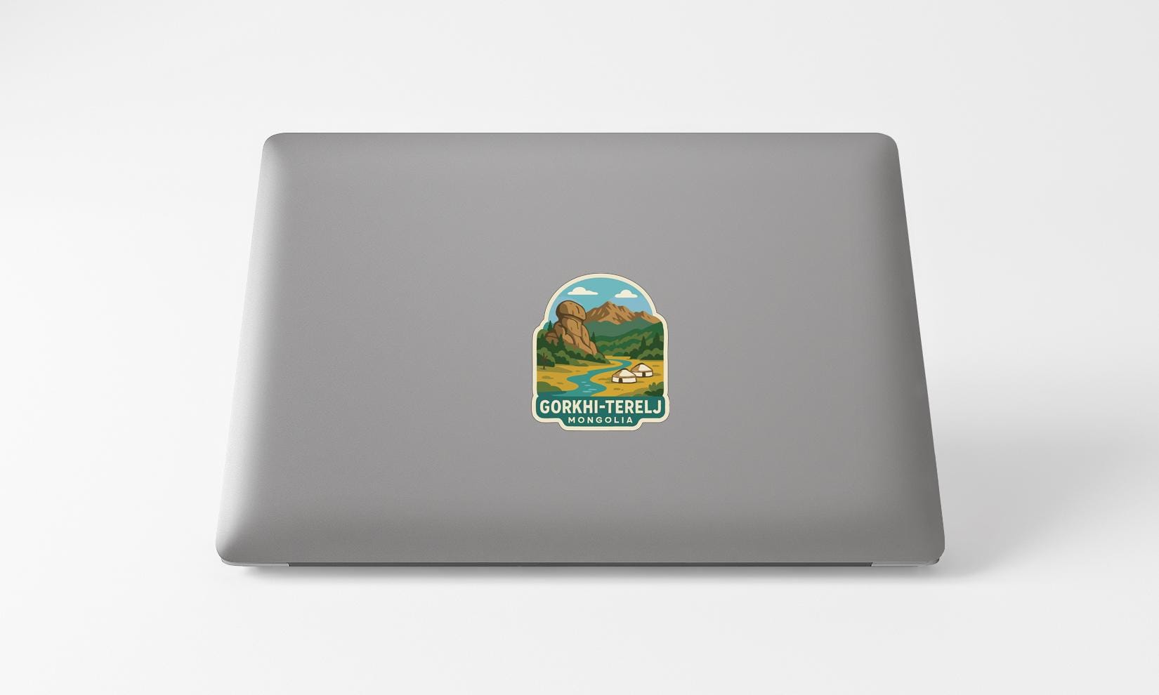a sticker on the back of a laptop with a mountain landscape and a river.