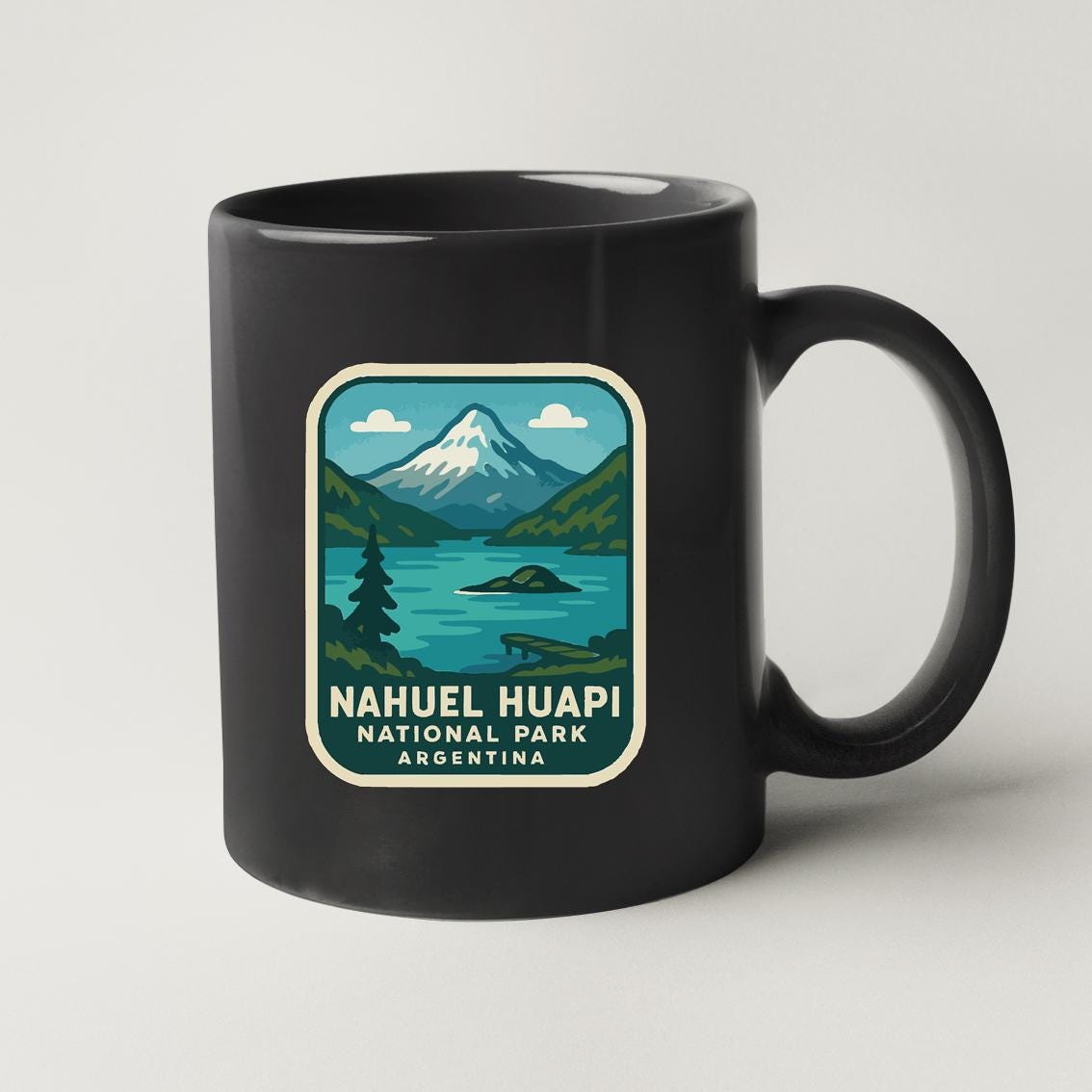 A black coffee mug with a graphic design depicting a mountain landscape and a lake, along with the text "Nahuel Huapi National Park Argentina".