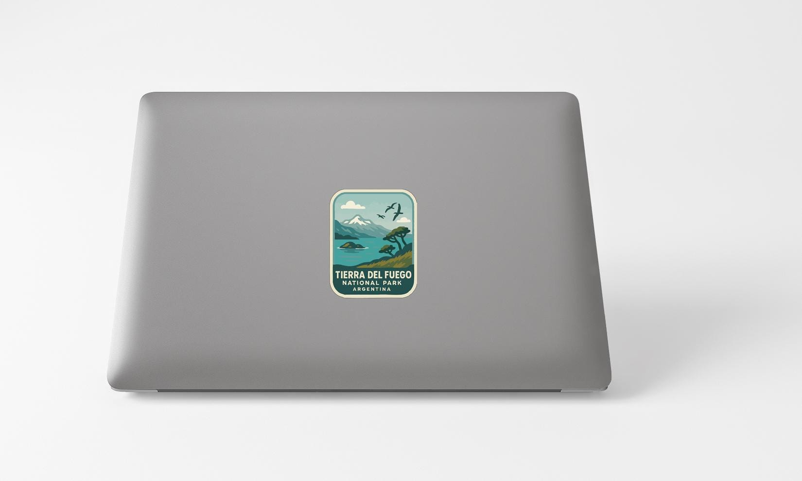 A sticker on the back of a laptop, depicting a scenic landscape with mountains and a body of water.