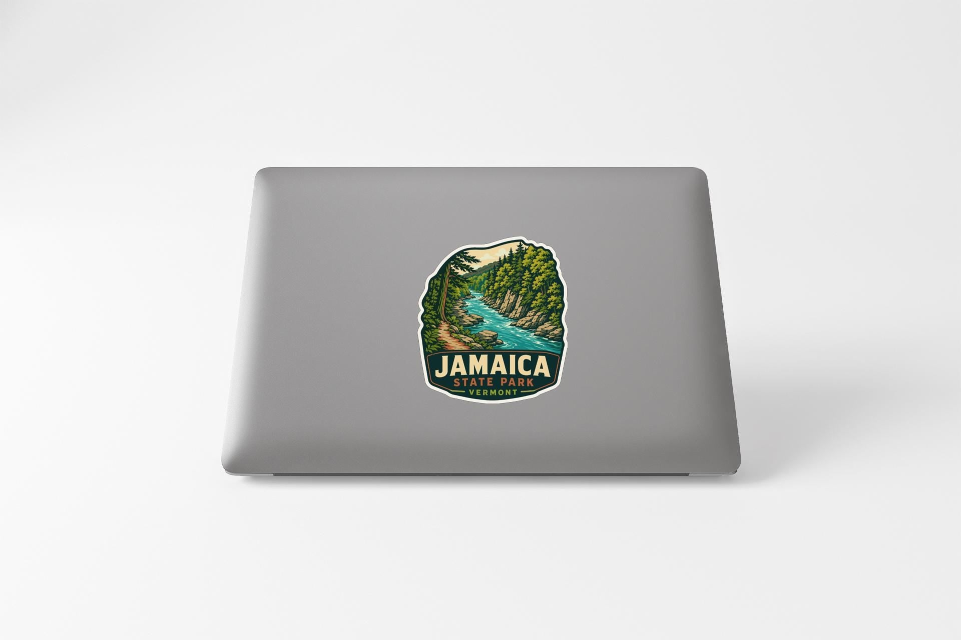 A sticker on the back of a laptop, depicting a scenic landscape with a river and mountains.