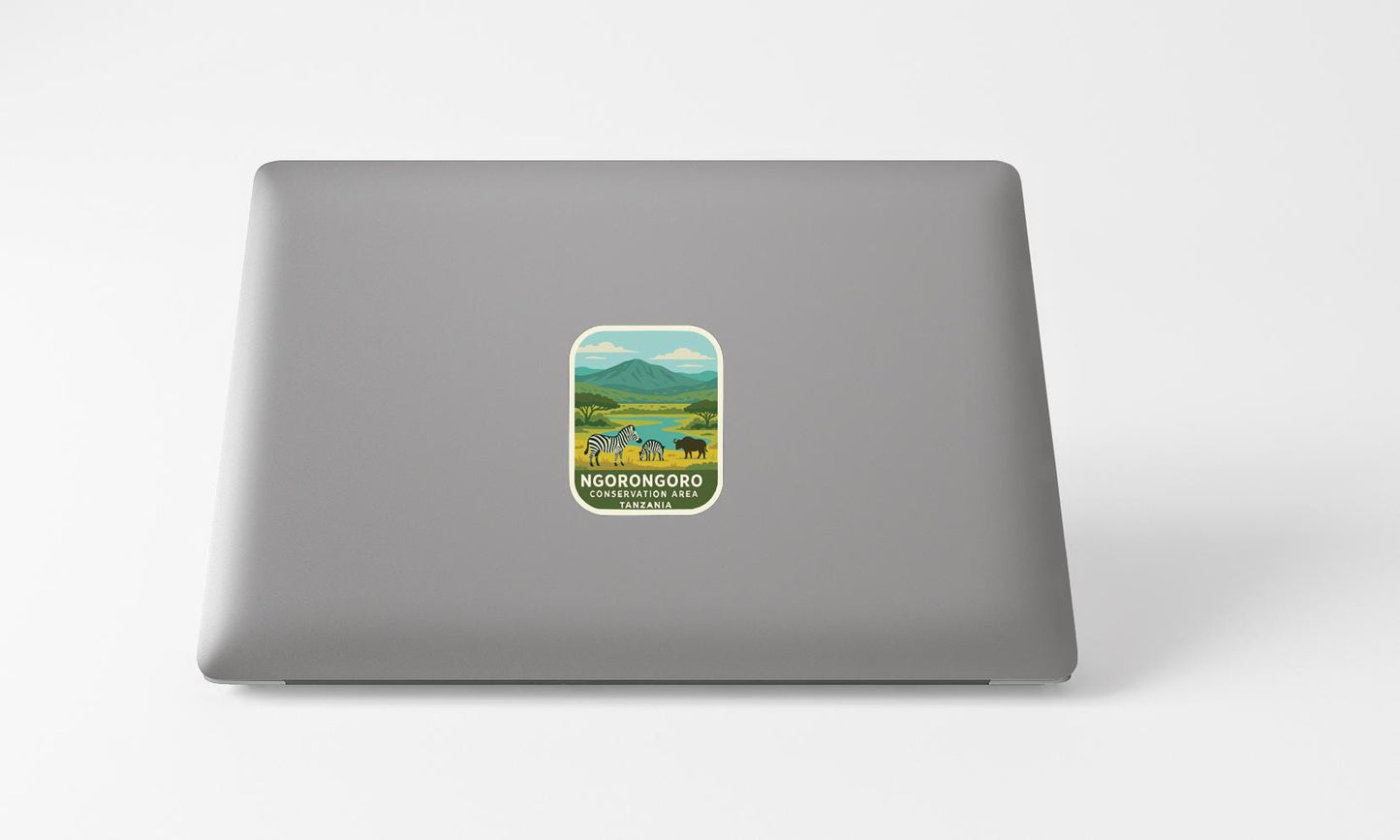 A sticker with a mountain landscape and a small illustration of a person is placed on the back of a laptop computer.