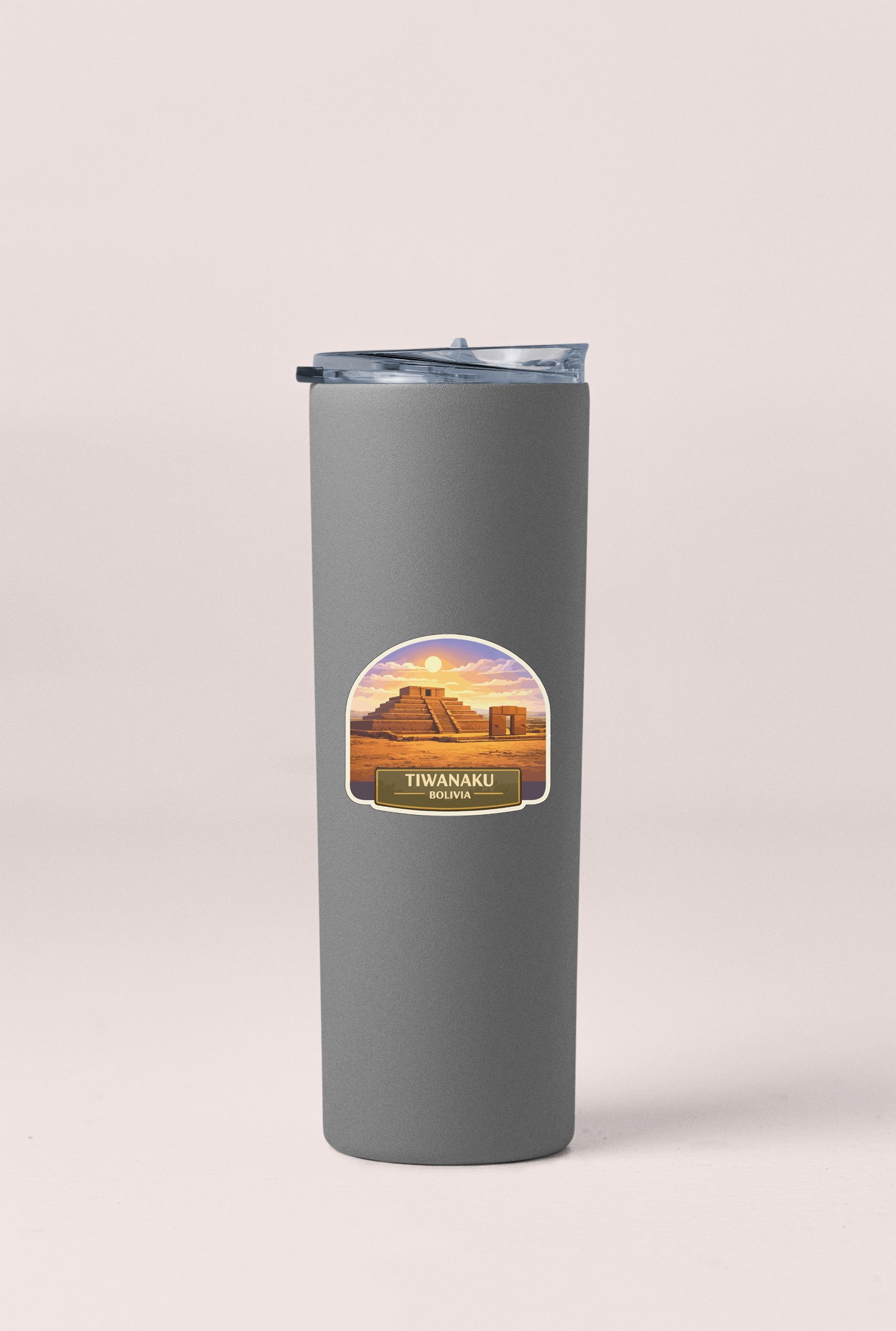 A gray insulated tumbler with a label that says "Tiwanaku, Bali" and features an illustration of a desert landscape with a pyramid in the background.