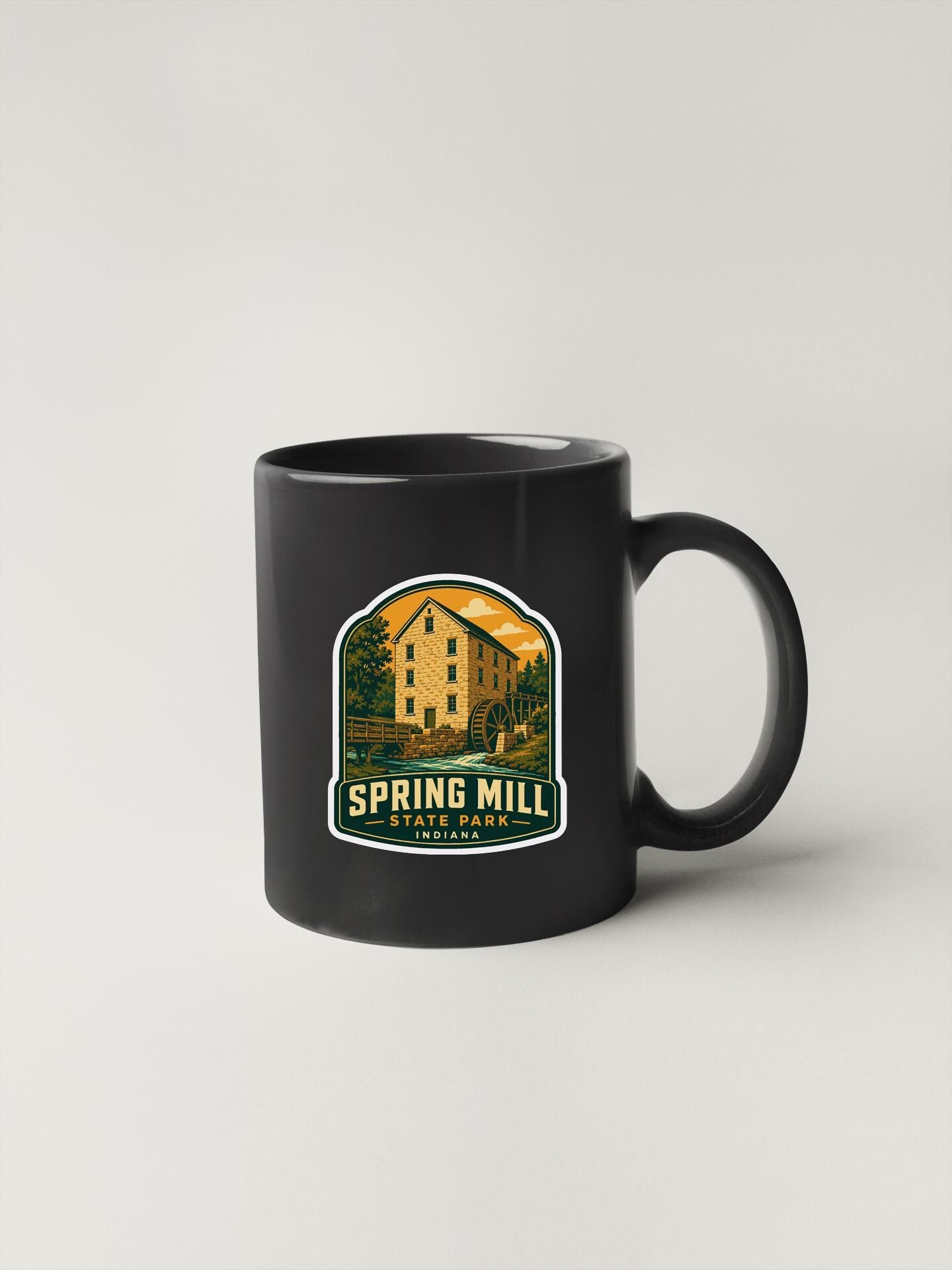 A black coffee mug with a graphic design featuring a building and the text "Spring Mill State Park, Indiana" printed on it.