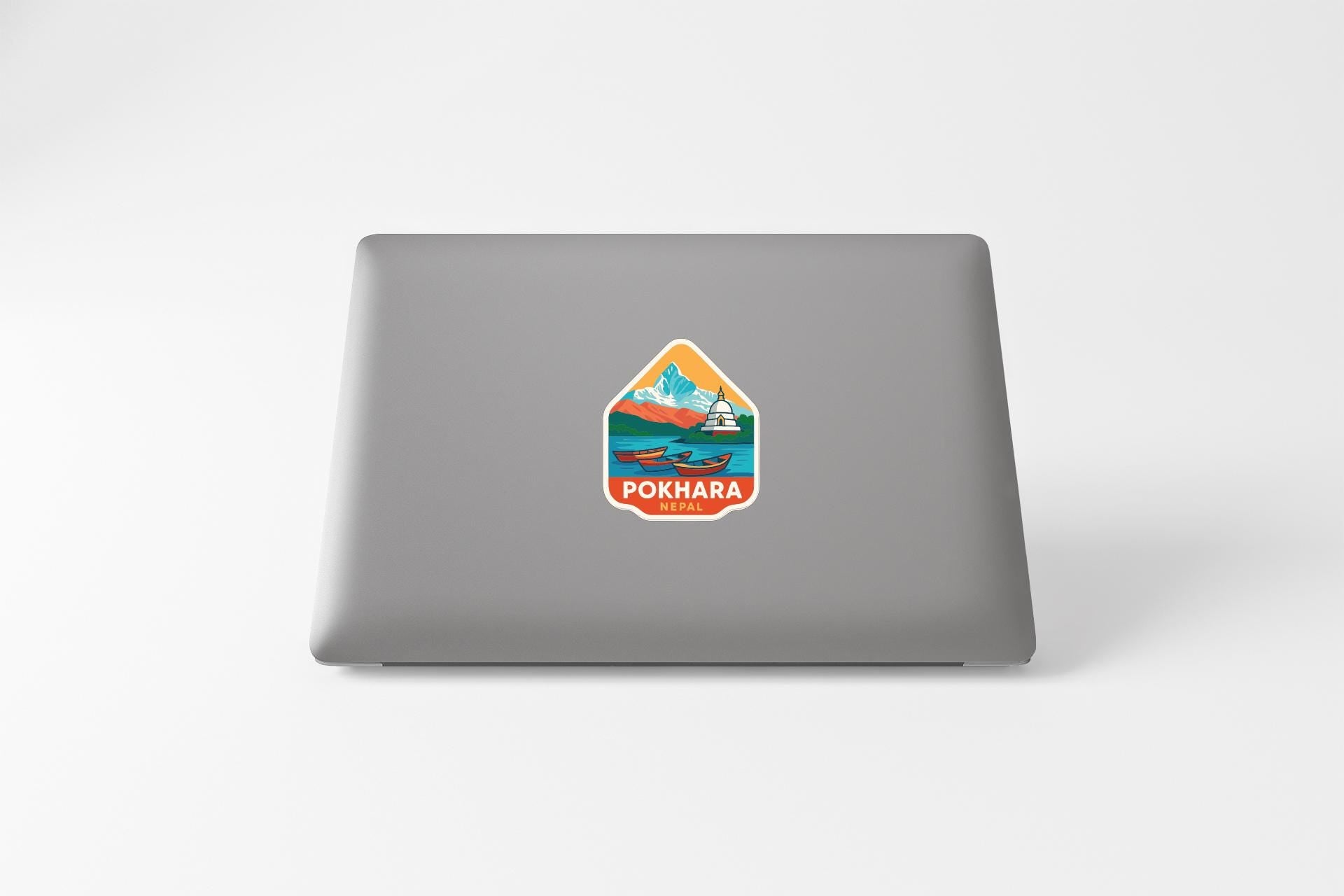 A sticker with a mountain landscape and a boat on a lake, with the text "POKHARA" printed on it.