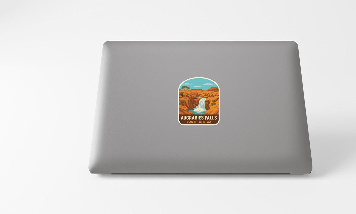 A sticker on the back of a laptop, depicting a waterfall in a desert landscape.