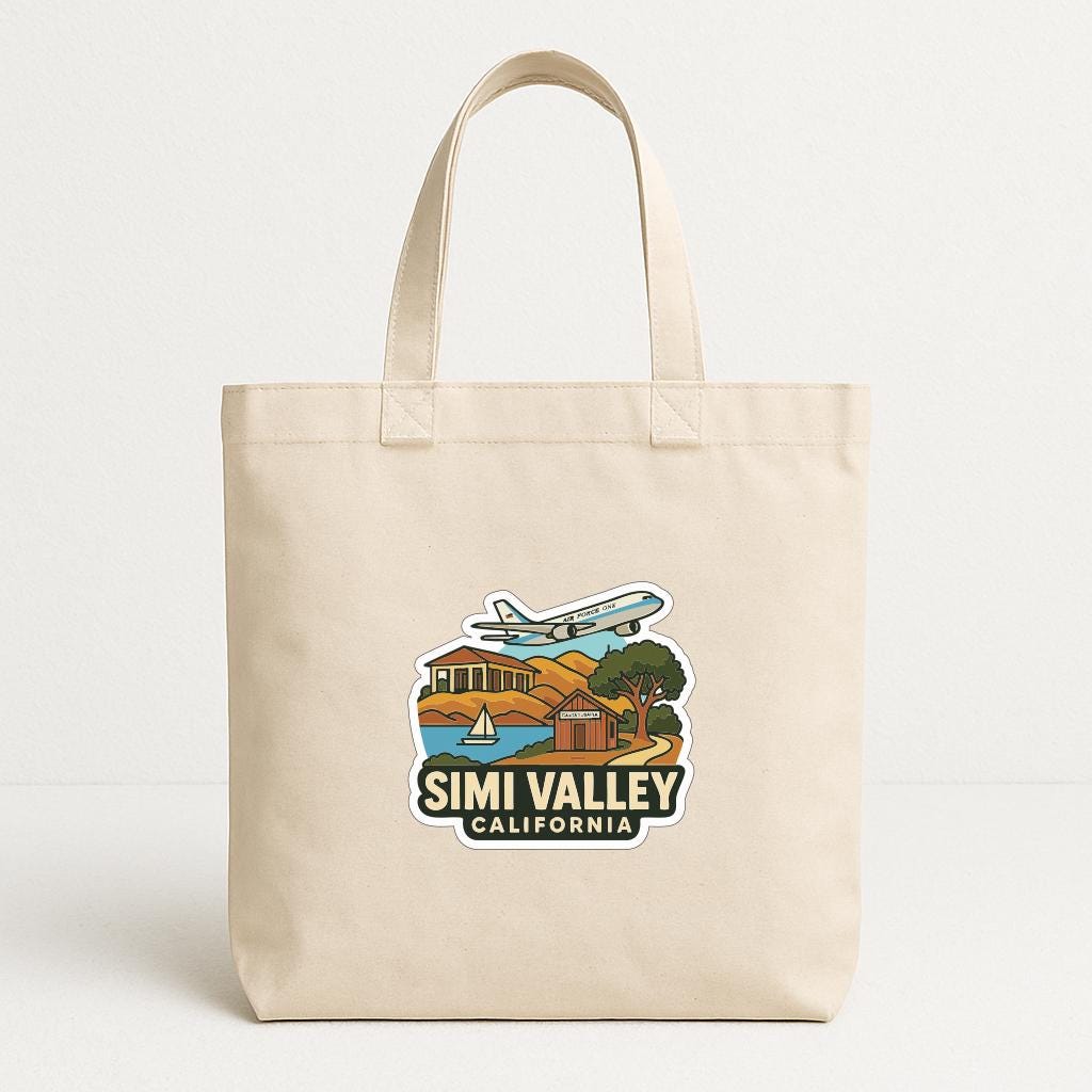 A beige tote bag with a printed design depicting a scenic landscape with a plane, buildings, and a body of water.