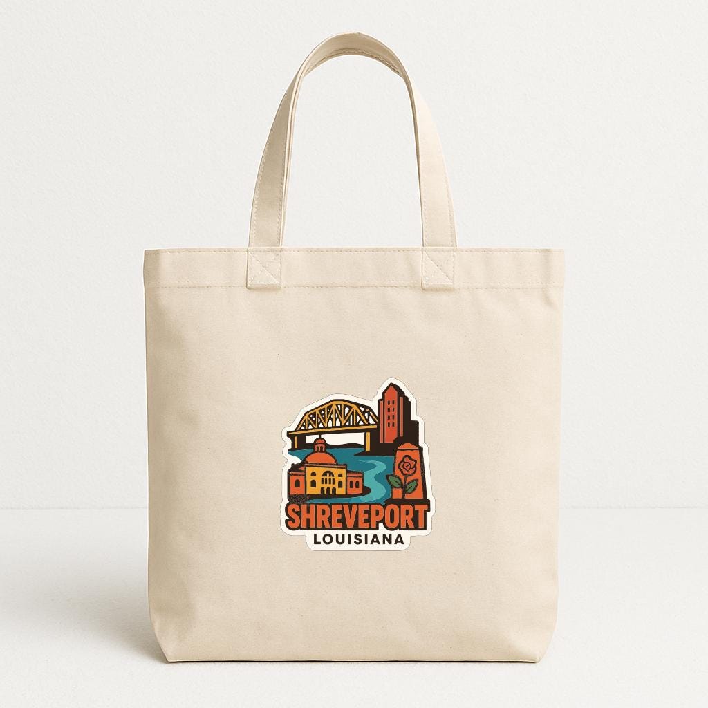 A beige tote bag with a printed design of Shreveport, Louisiana, featuring a bridge, buildings, and a river.