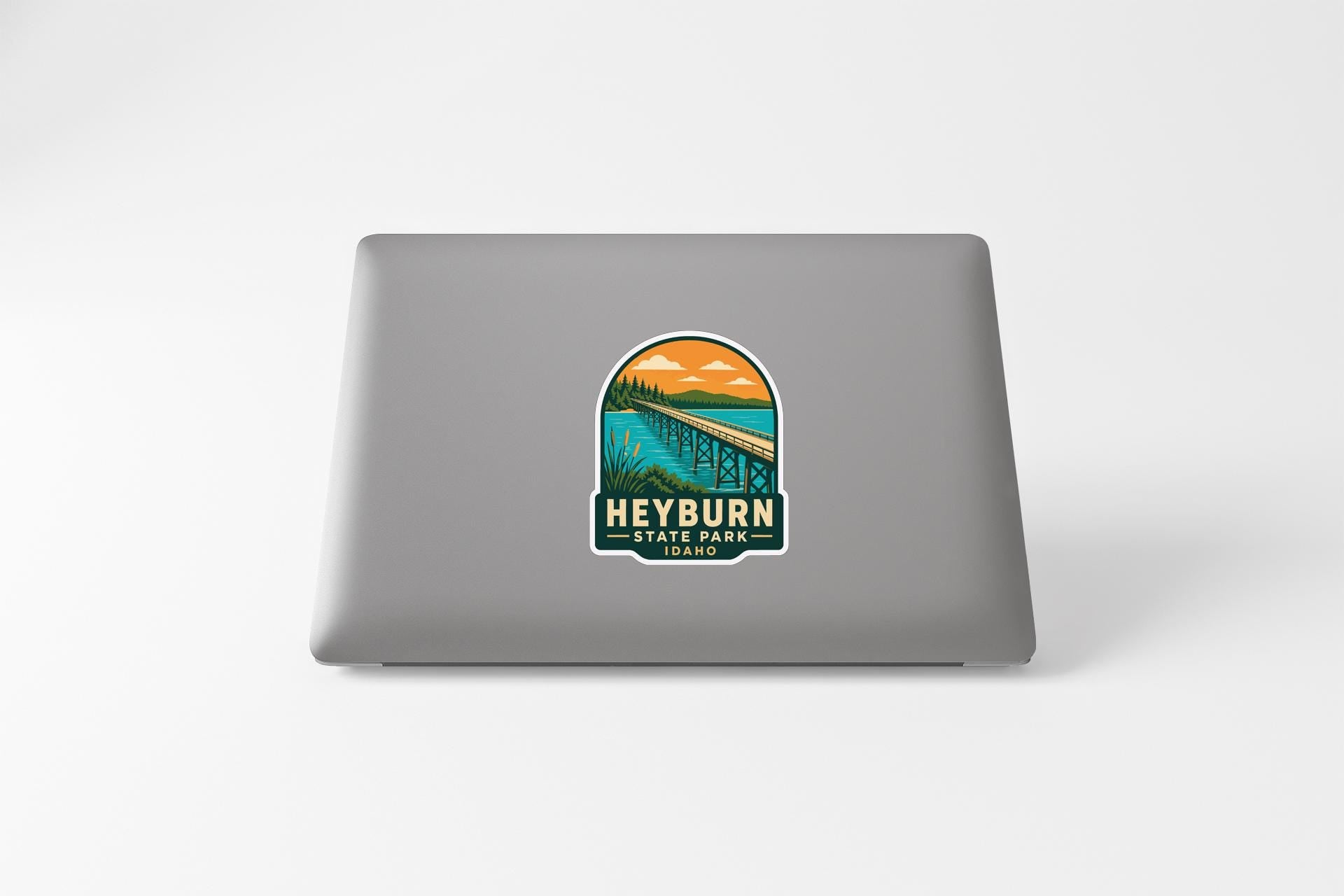a sticker on the back of a laptop that displays a scenic landscape with a bridge and a body of water.