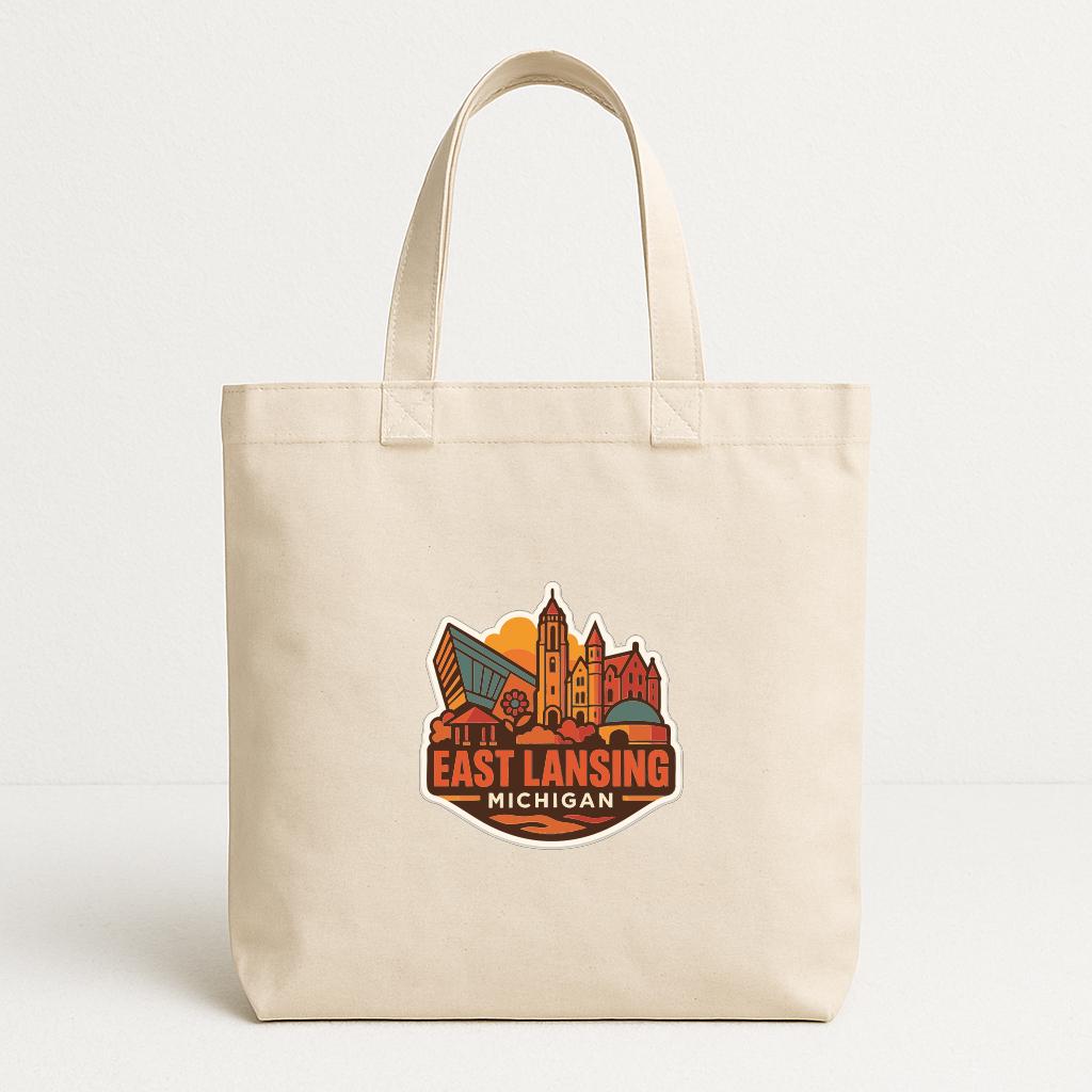 A beige tote bag with a printed design featuring a city skyline and the text "EAST LANSING MICHIGAN".