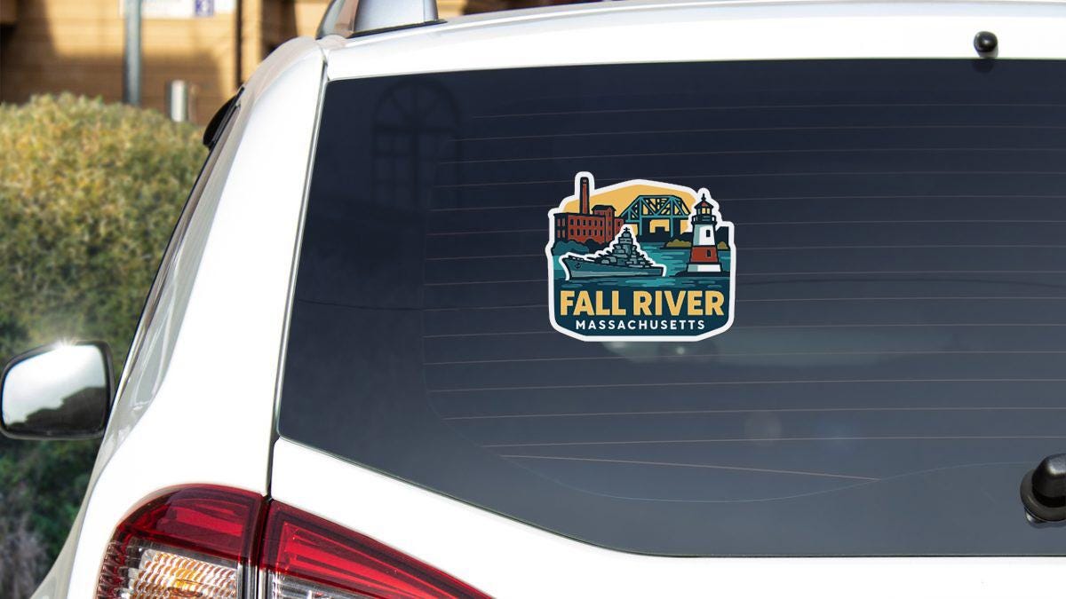 A sticker on the rear window of a white vehicle, depicting a cityscape with a river and buildings, along with the text "FALL RIVER MASSACHUSETTS".