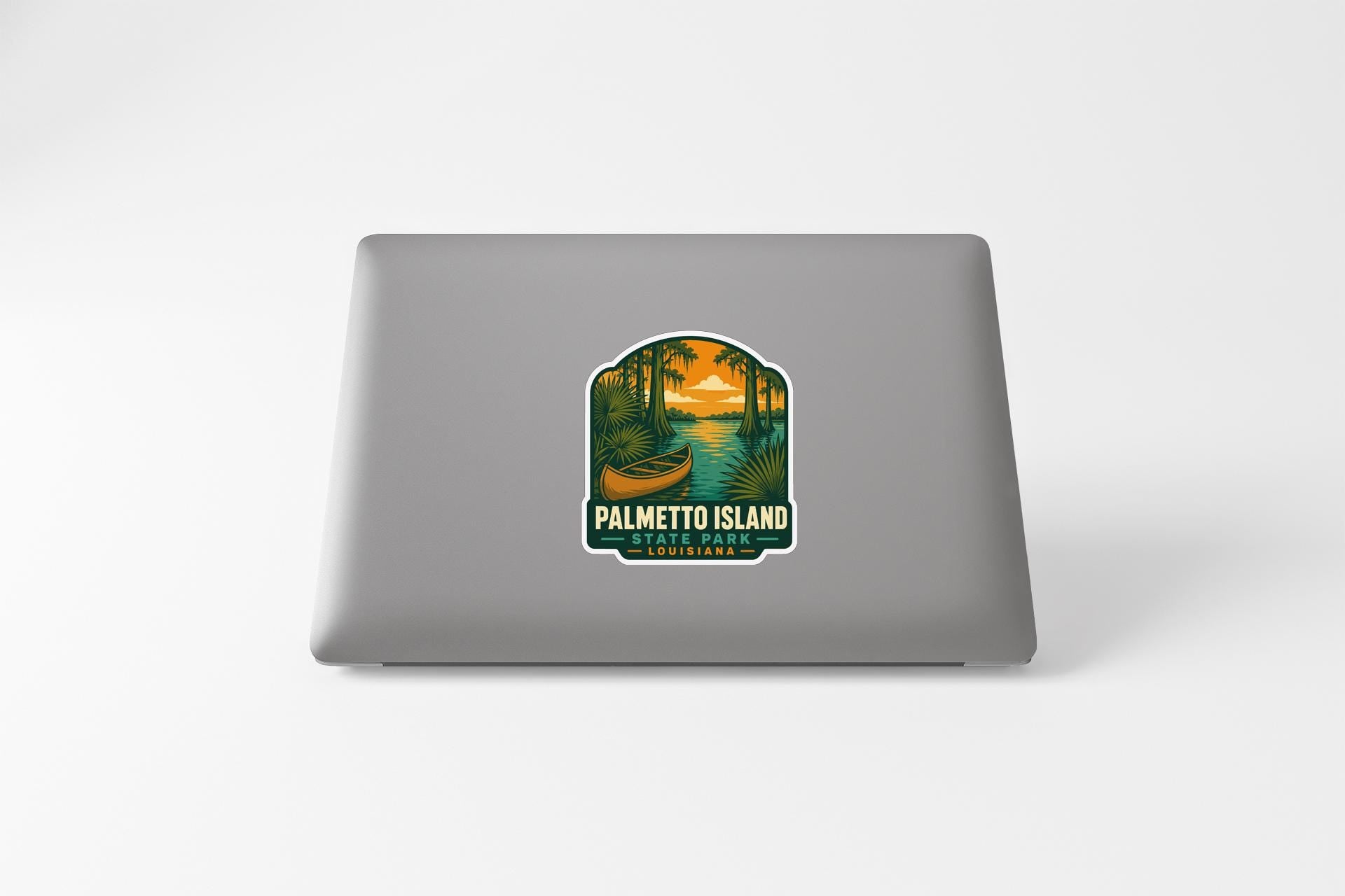 A sticker on the back of a laptop, depicting a scenic landscape with palm trees, a boat, and a sunset.