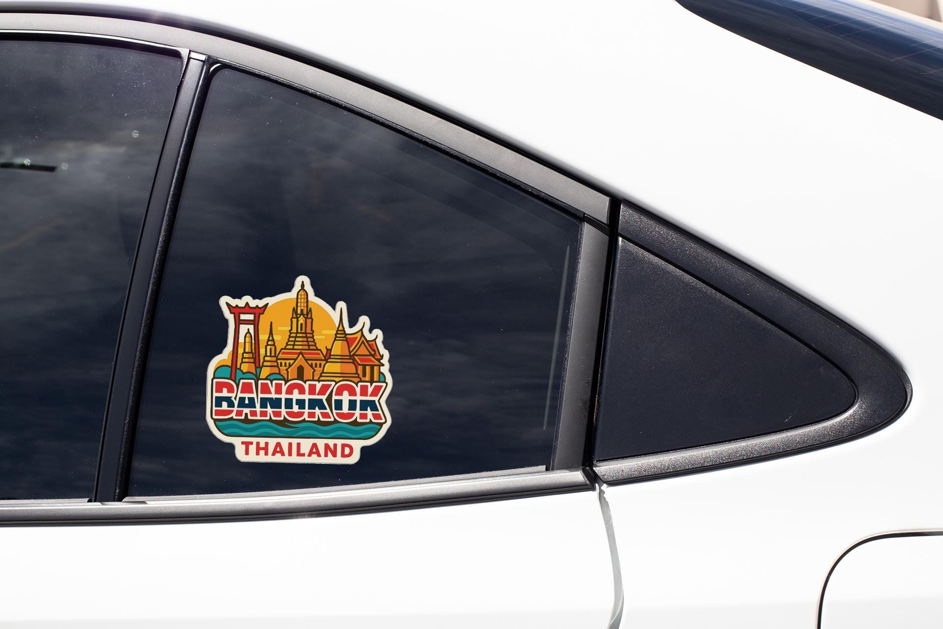 A sticker on the side of a car window, depicting a cityscape with a temple, and the word "BANGKOK" written below it.