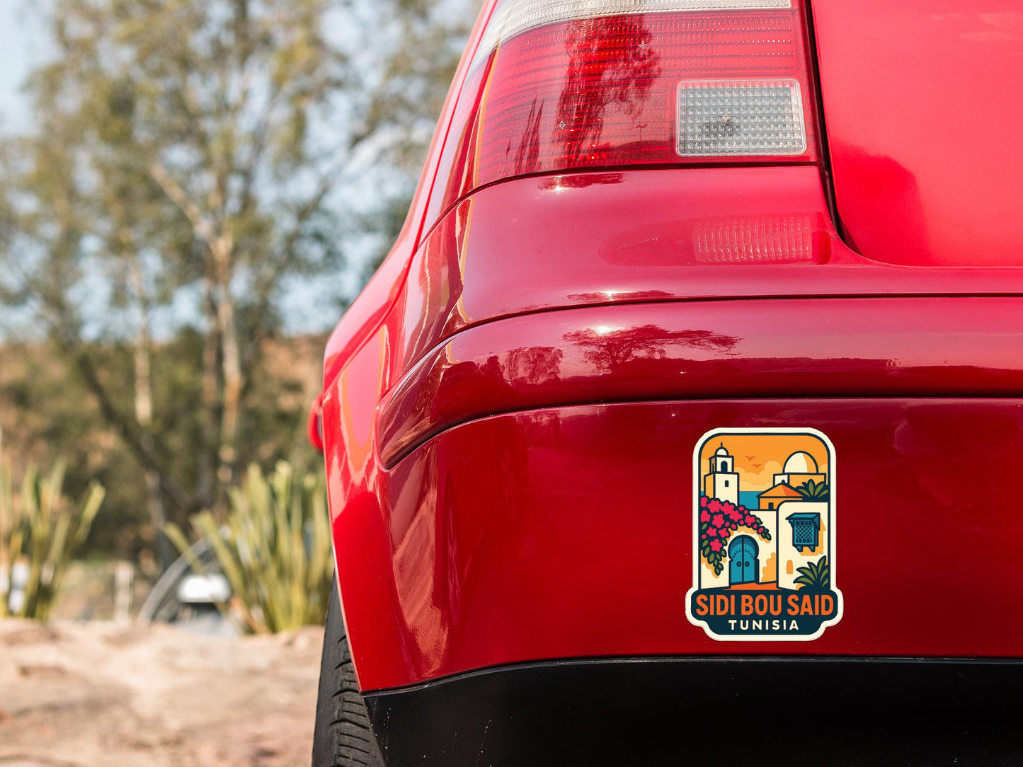the rear end of a red car with a sticker on the trunk that says "SIDI BOU SAID TUNISIA".