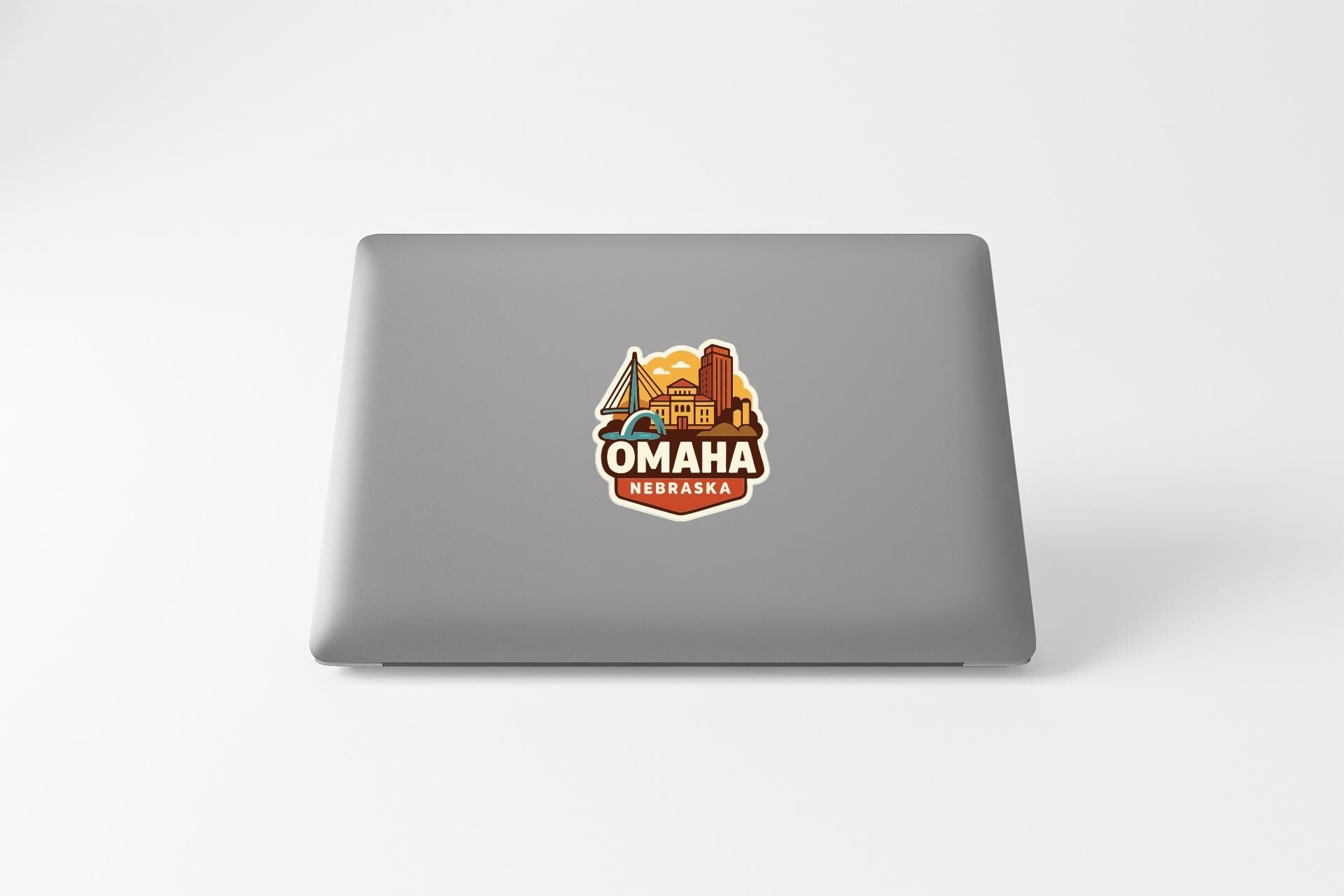 a sticker with the text "OMAHA NEBRASKA" on a grey laptop.