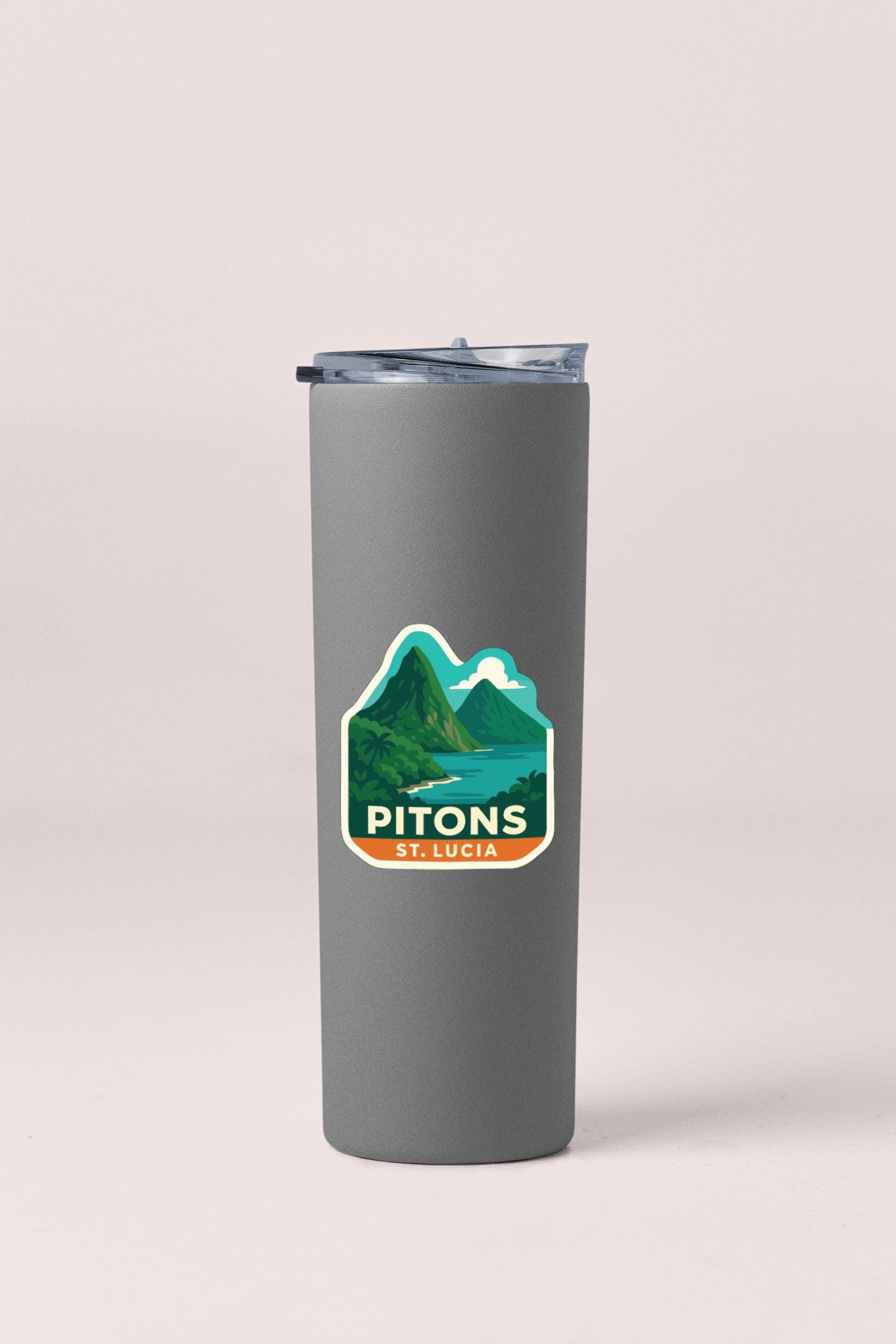 A gray insulated tumbler with a sticker depicting a mountain landscape and the text "PITONS ST. LUCIA".