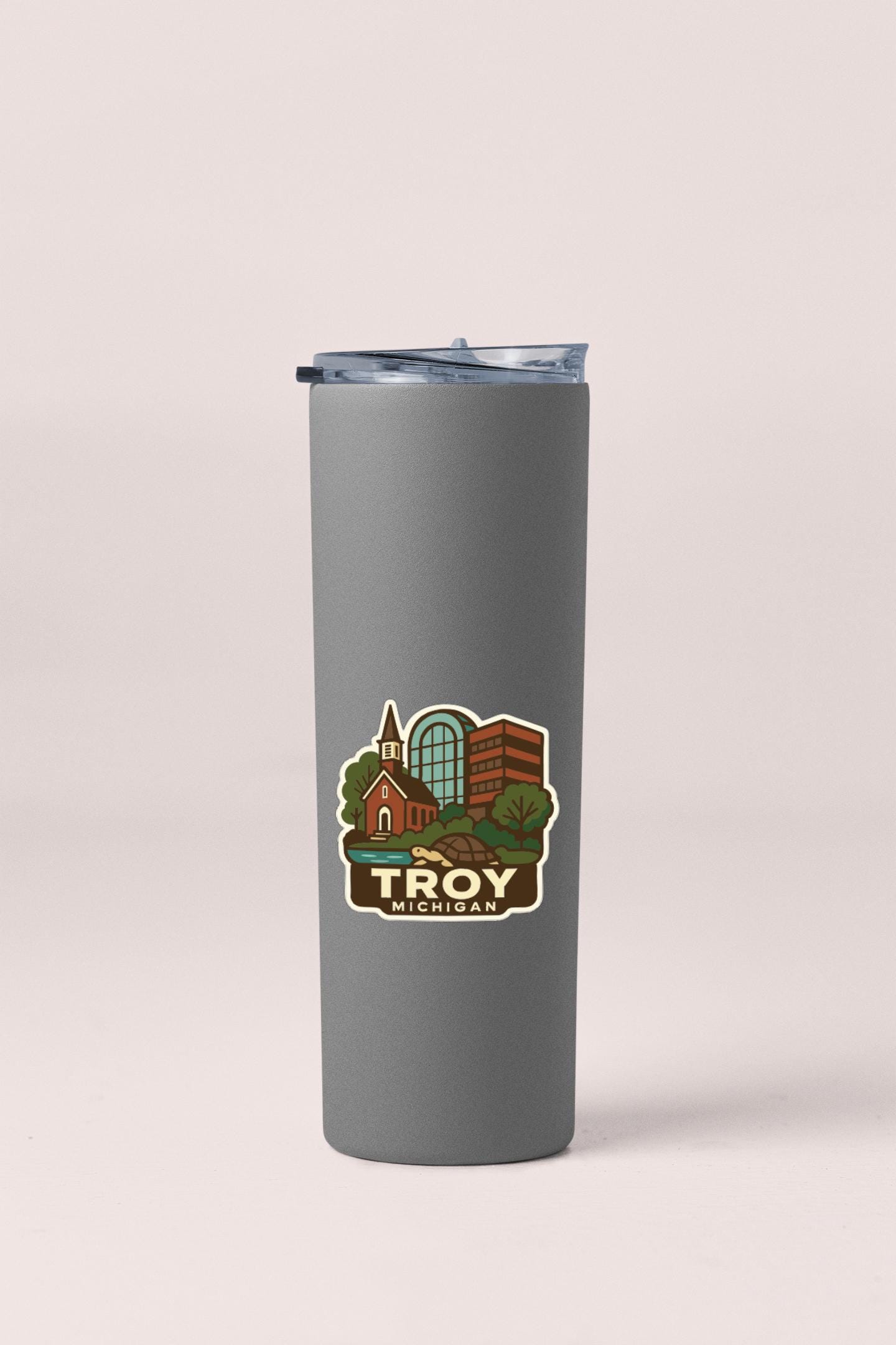 A gray insulated tumbler with a sticker depicting a cityscape of Troy, Michigan.