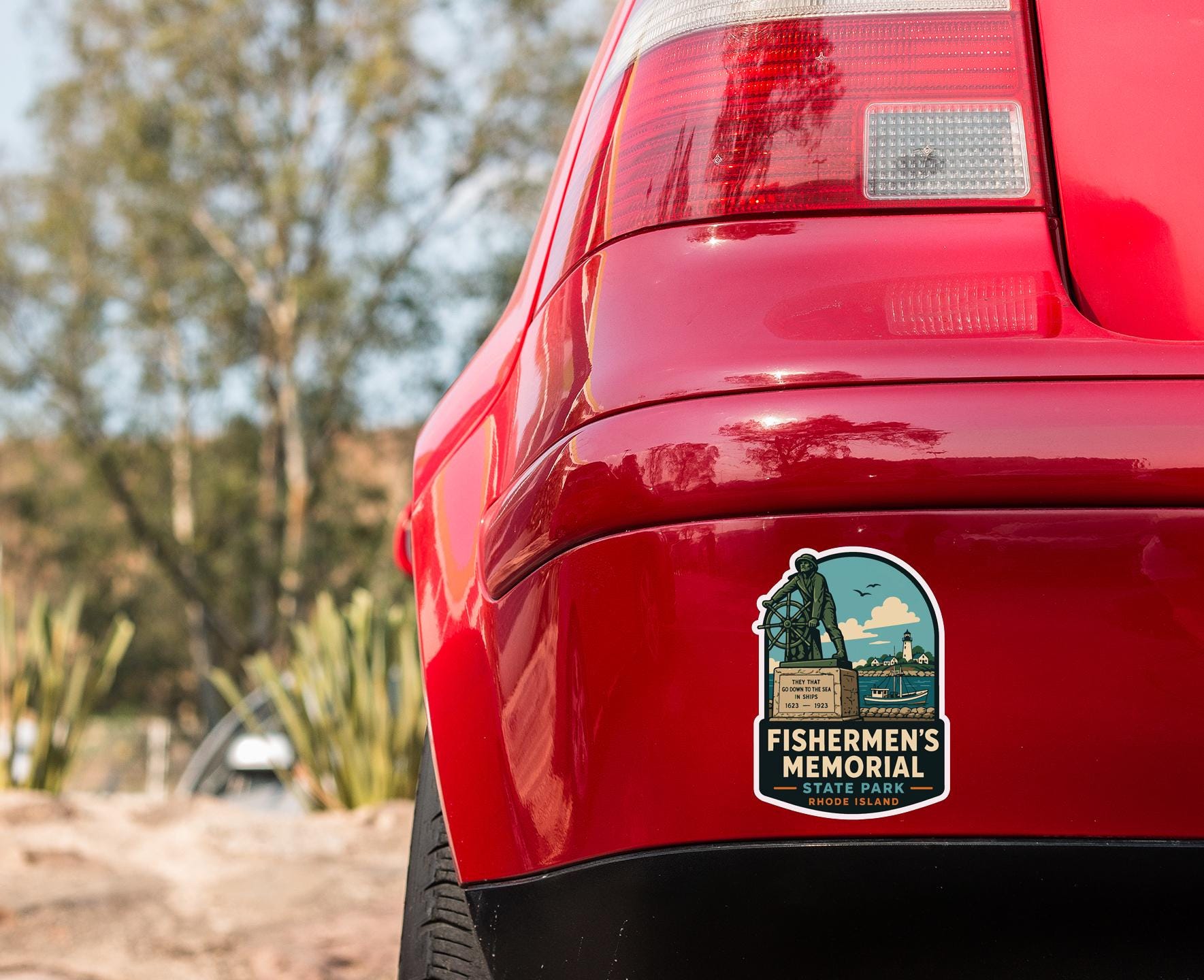 the rear end of a red car with a sticker on the bumper that says "FISHERMAN'S MEMORIAL RHODE ISLAND".
