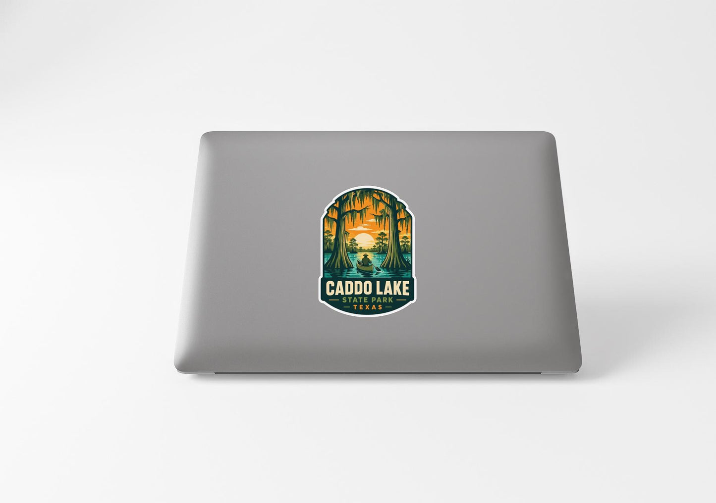 a sticker with a scenic illustration of a lake and trees, along with the text "CADDO LAKE" and "TEXAS" printed on it.