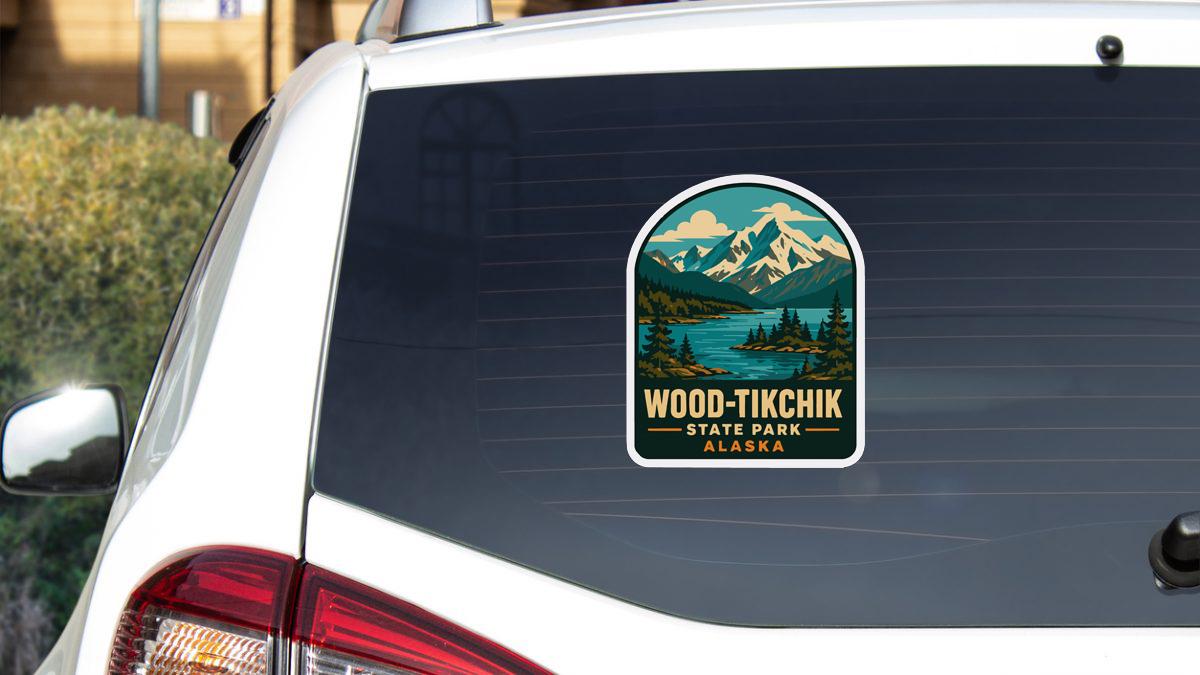A sticker on the rear window of a white car, depicting a scenic landscape with mountains and a lake.
