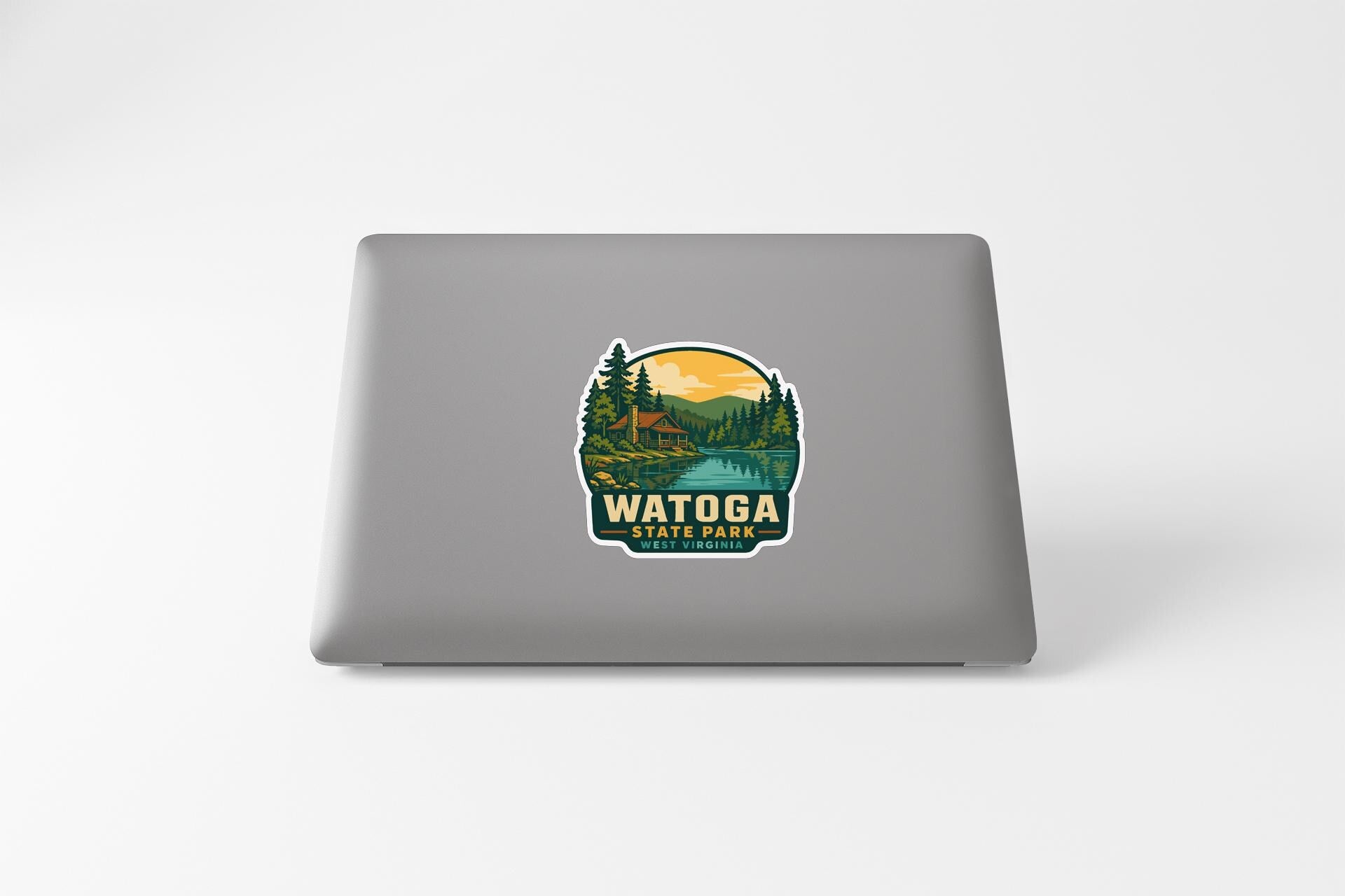 A sticker on the back of a laptop that features a scenic landscape with a lake, trees, and mountains, along with the text "WATOGA STATE PARK".