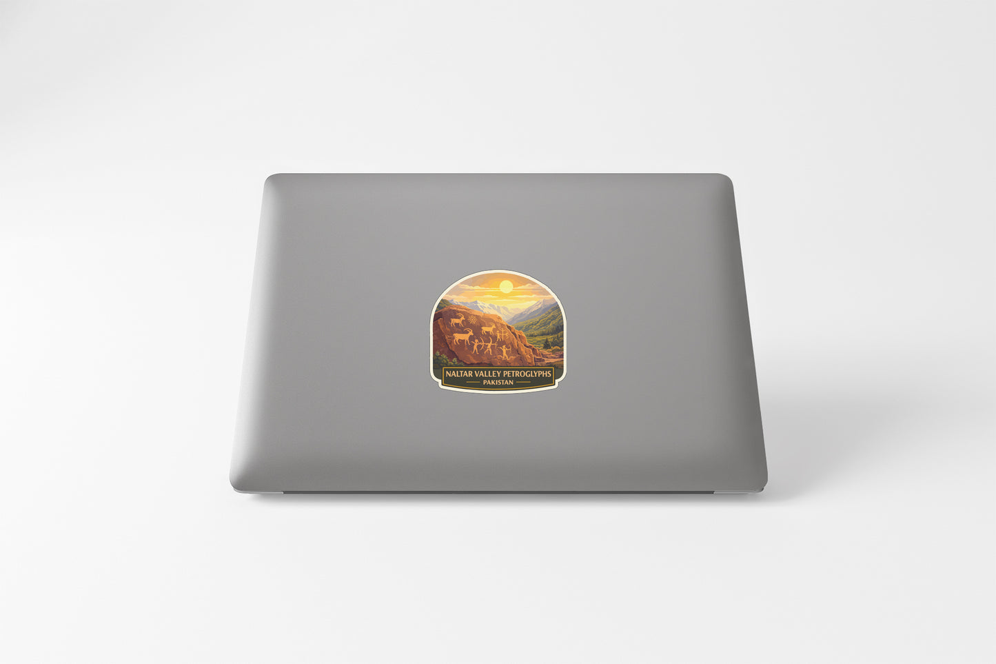A sticker on the back of a laptop, depicting a scenic landscape with mountains and a sunset.
