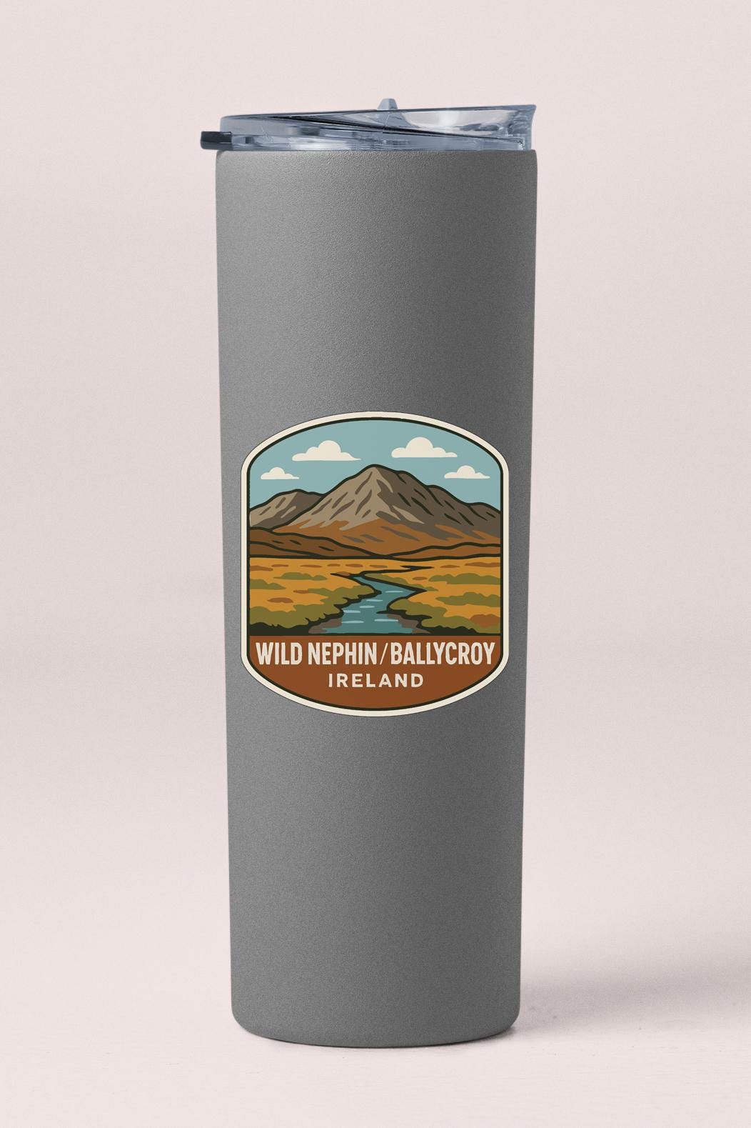 A gray tumbler with a label depicting a mountain landscape and a river.