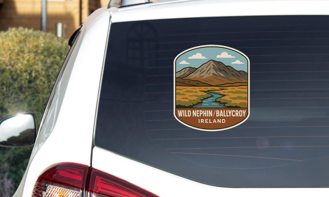a sticker on the rear window of a car, depicting a scenic landscape with mountains, a river, and a sky with clouds.