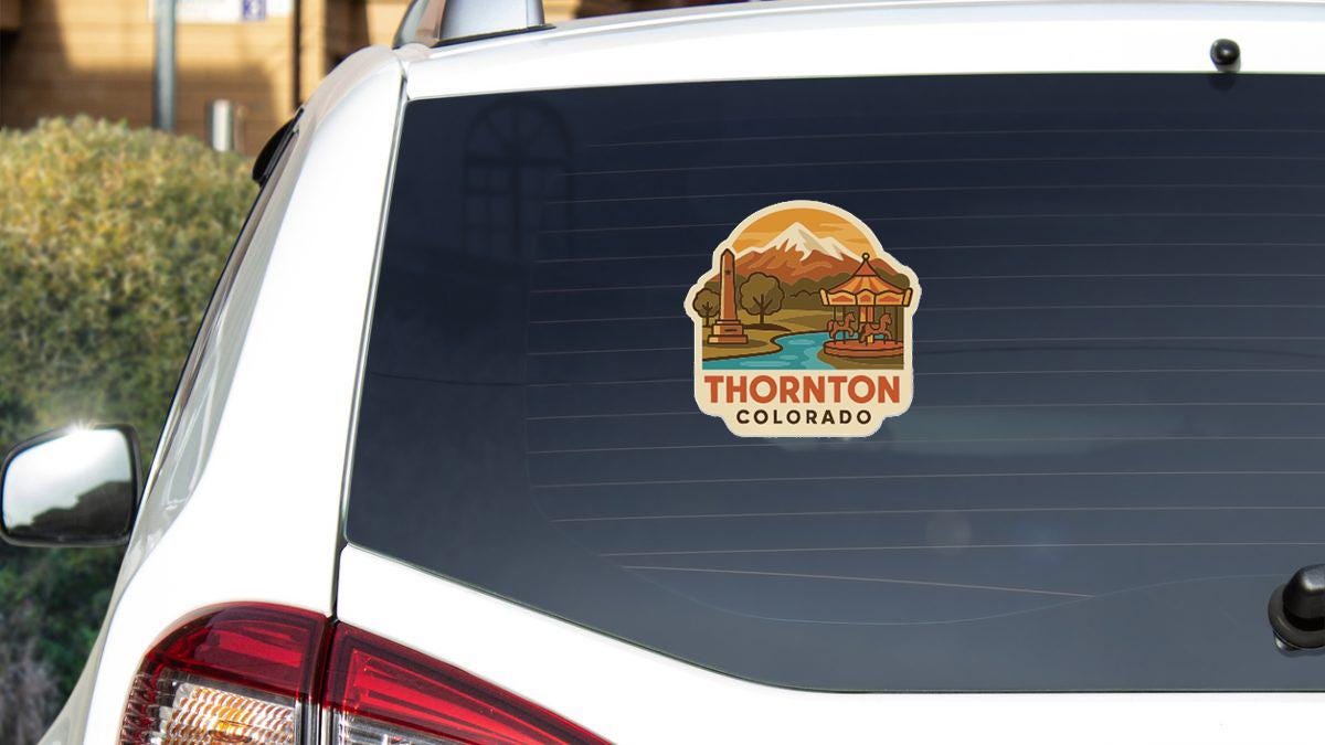 A sticker on the rear window of a white car, depicting a scenic landscape with mountains and a river, along with the text "THORNTON COLORADO".