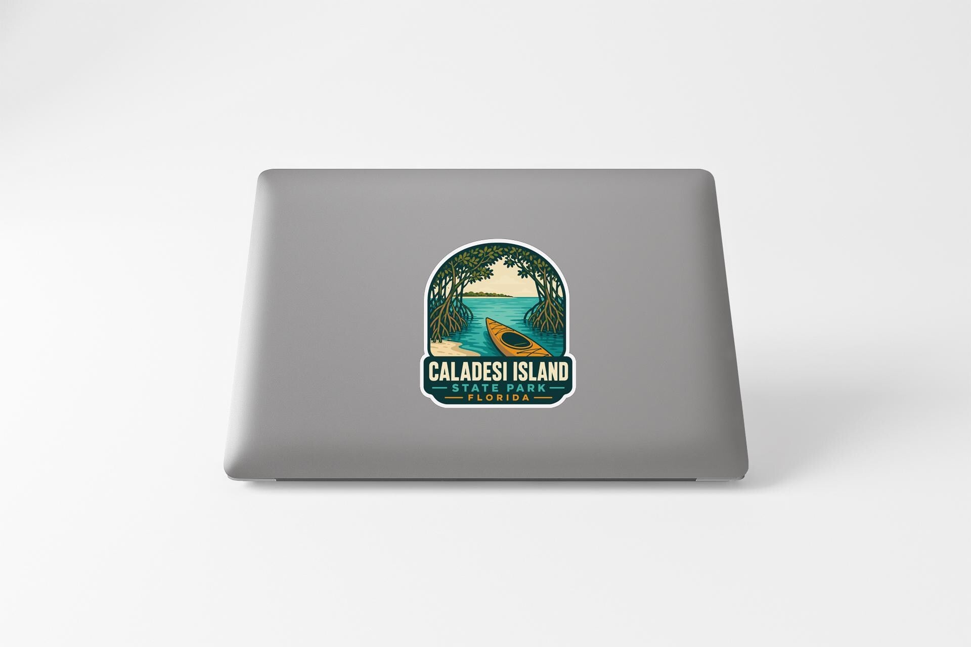 A sticker on the back of a laptop, depicting a tropical scene with a canoe and palm trees.