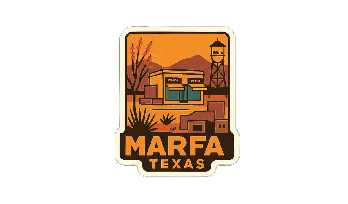 a sticker or label with a stylized illustration of a building and a water tower, set against a desert landscape with mountains in the background.