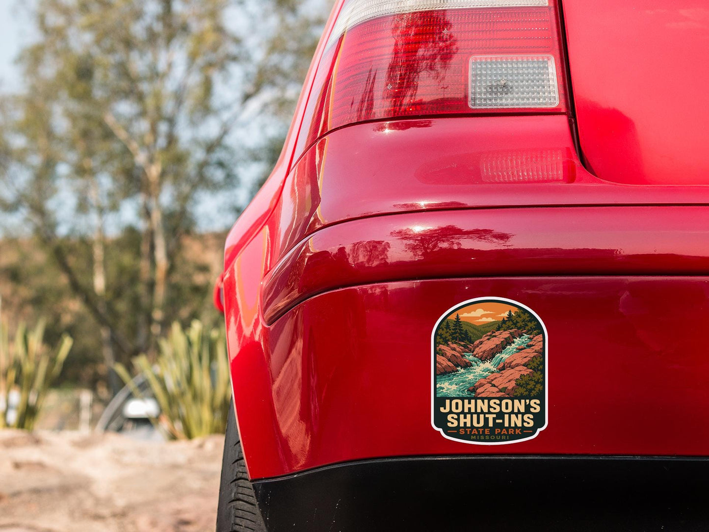 the rear end of a red car with a sticker on the bumper that says "Johnson's Shut-Ins".