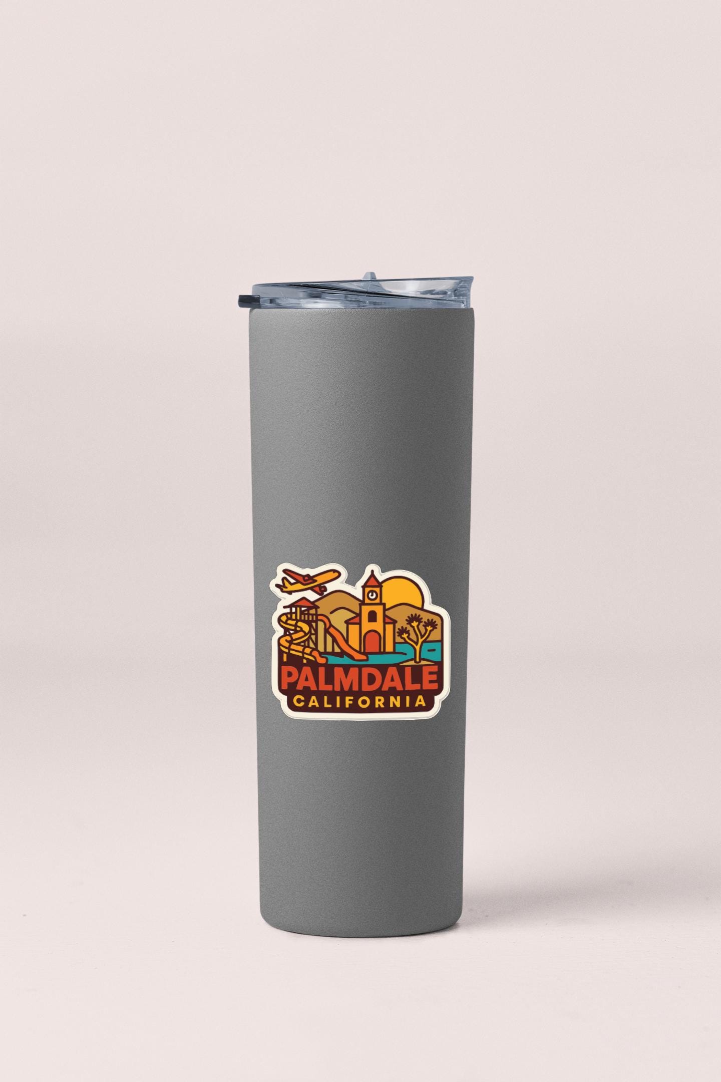 A gray insulated tumbler with a sticker depicting the city of Palmdale, California.