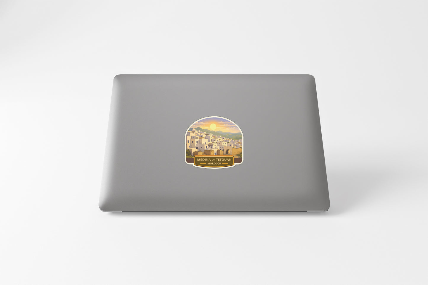 a sticker with a scenic illustration of a coastal town, placed on the back of a laptop.