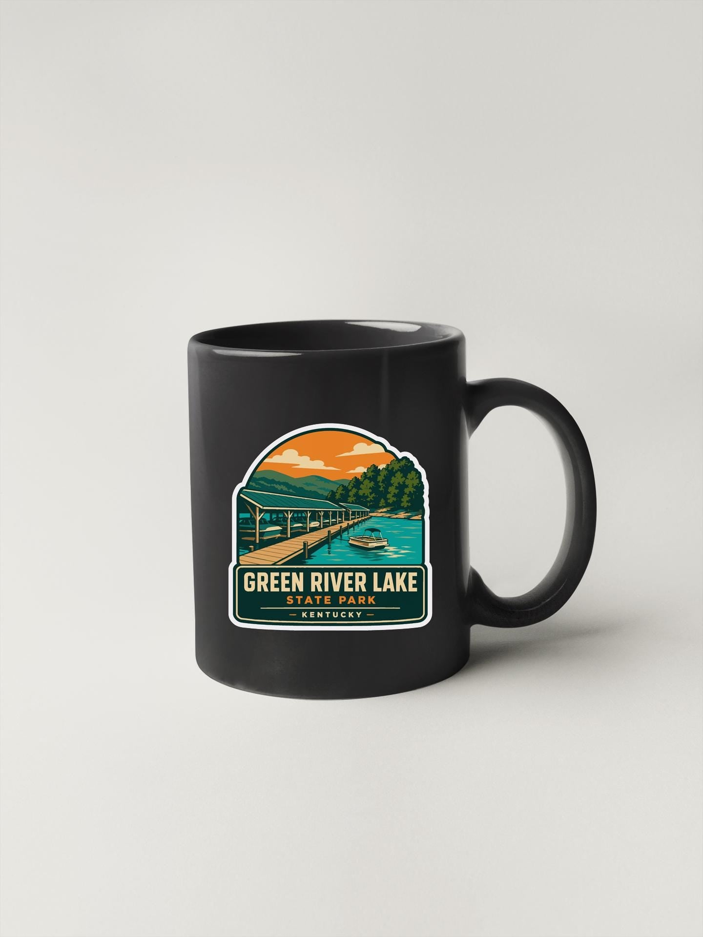 A black coffee mug with a graphic design depicting a scenic view of Green River Lake State Park in Kentucky.